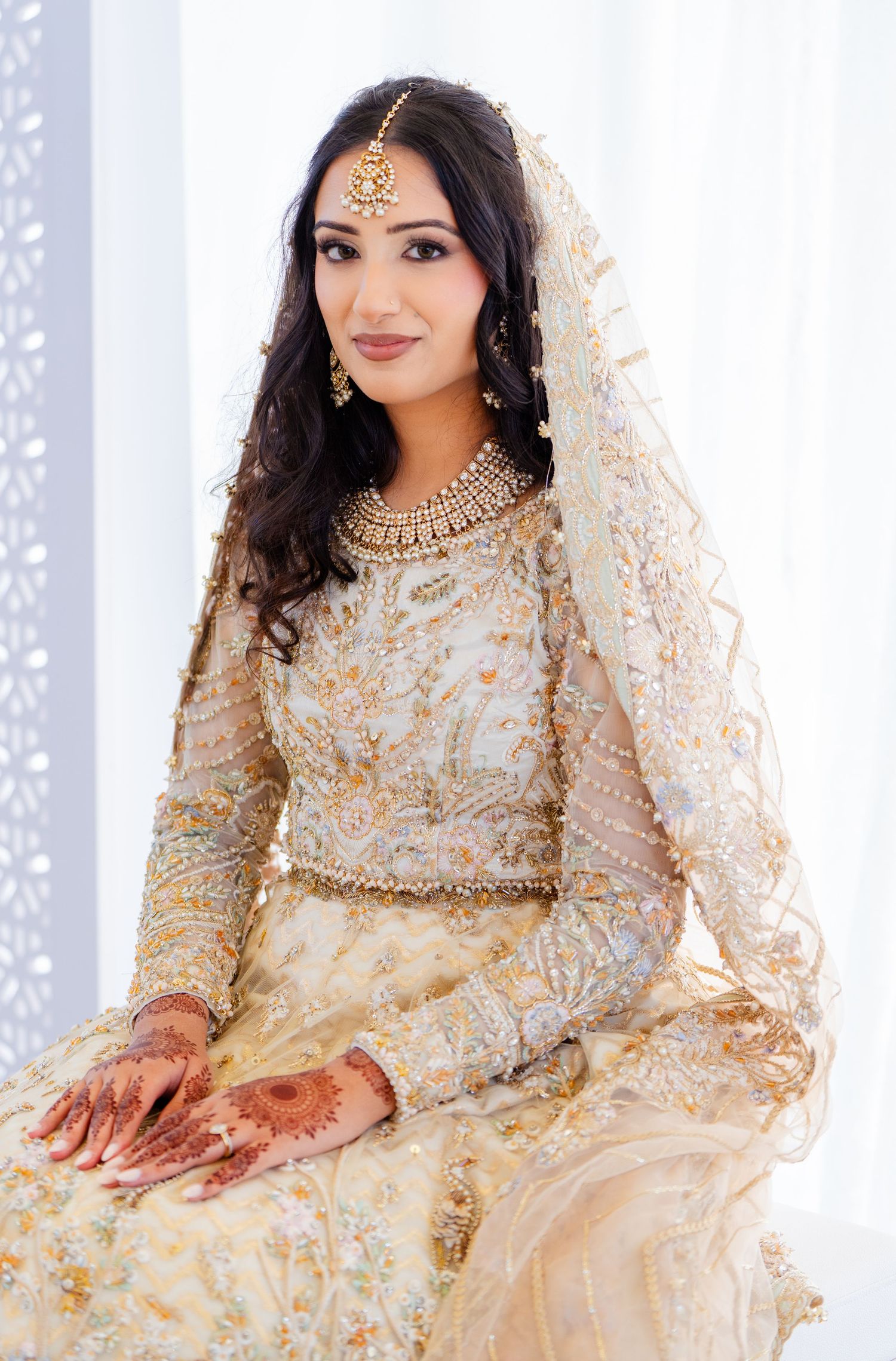 Luxurious cream wedding lengha with detailed embroidery and traditional jewelry.