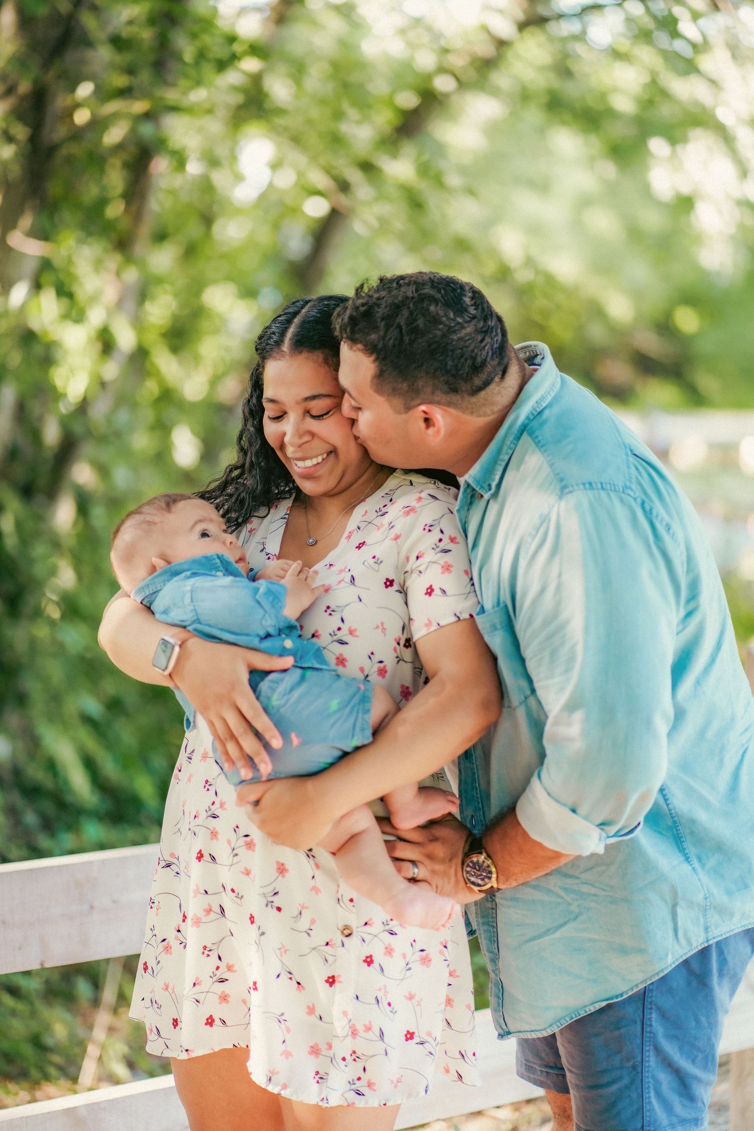 Family photo session in a park showing tender moments with a baby in blue.
