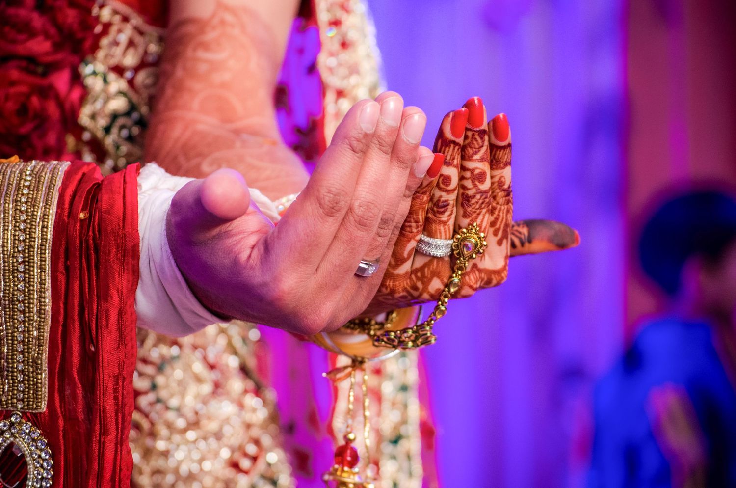 Wedding ceremony details with purple lighting and traditional Indian jewelry.