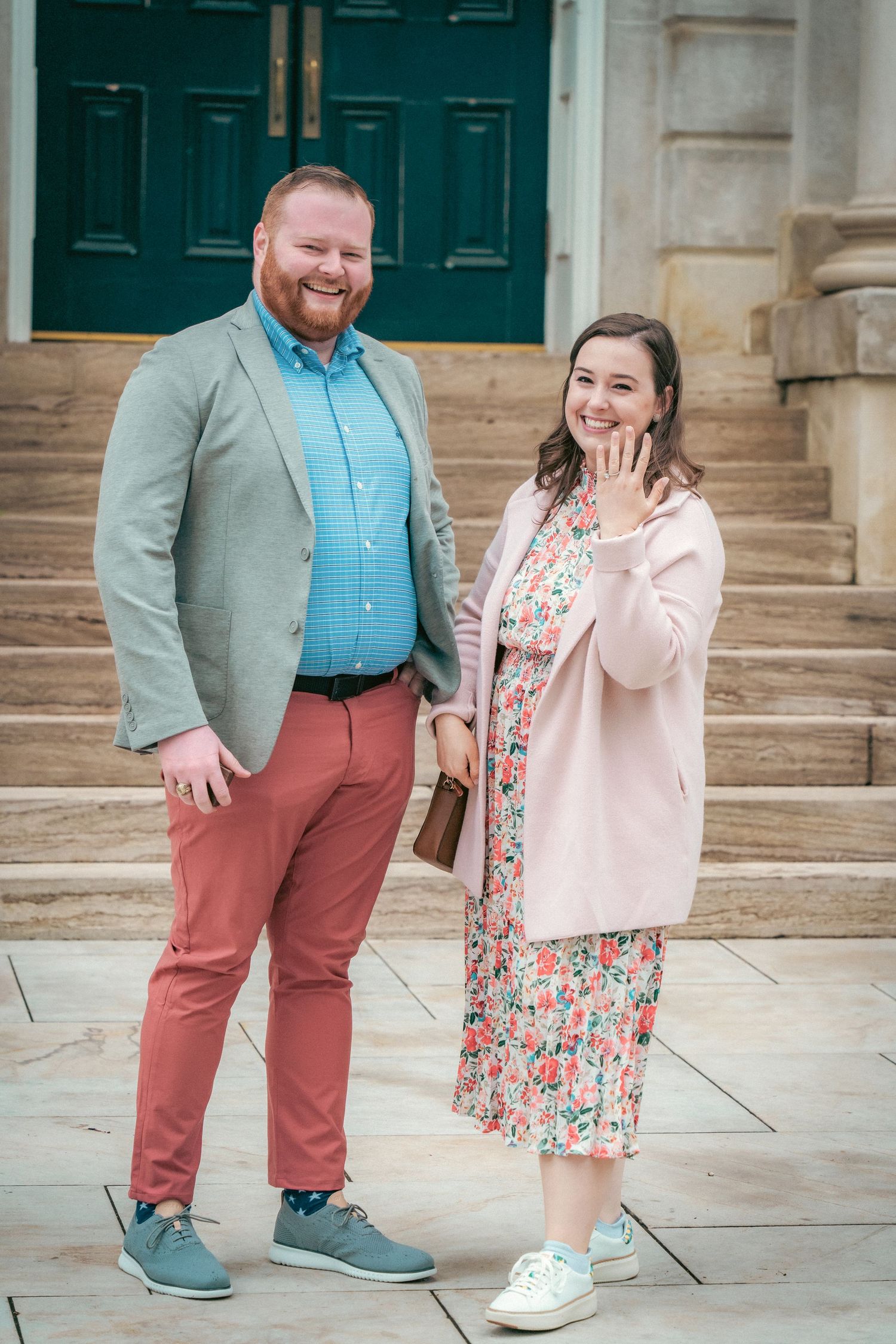 Couple in spring attire poses on architectural stone steps.
