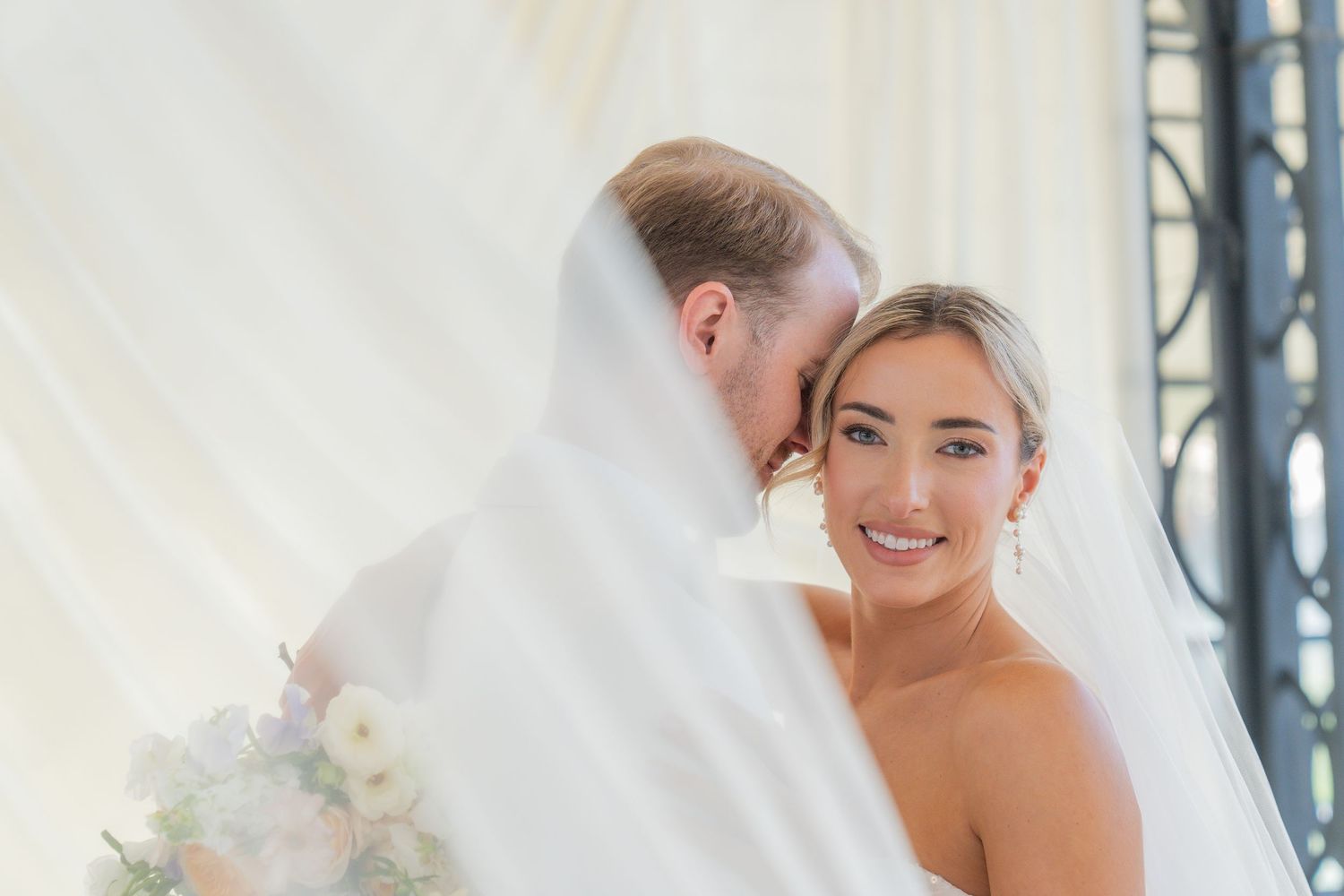 Elegant white wedding dress photographed against light backdrop with romantic styling.