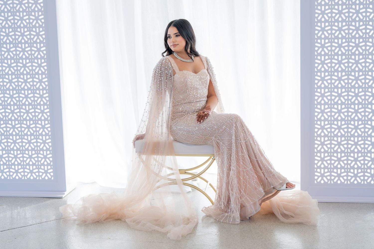 Bridal portrait session featuring a flowing white dress against decorative lattice panels.