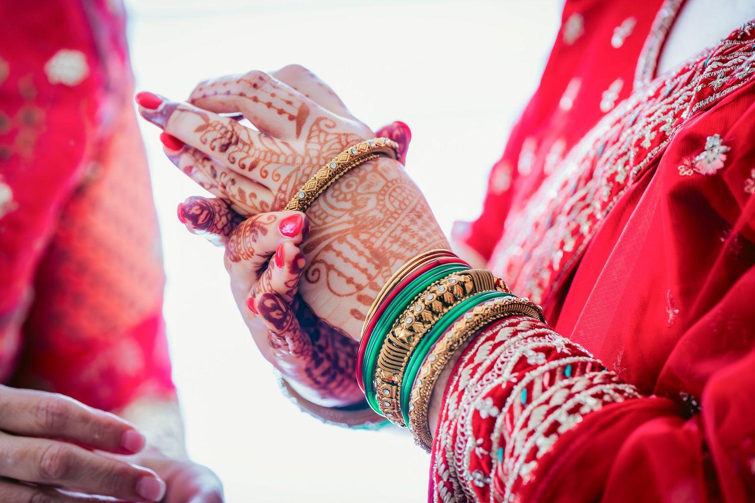 Detail shot of traditional Indian bridal jewelry and red wedding attire.