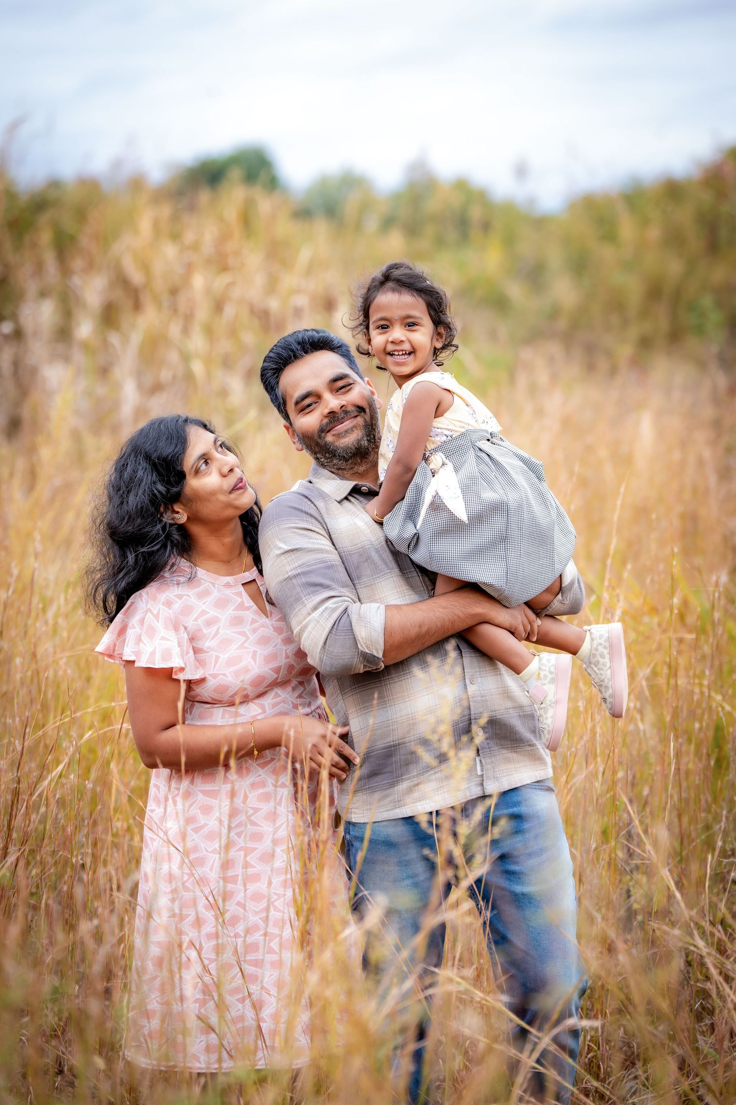 A family sharing a joyful moment together in a field of tall golden grass.