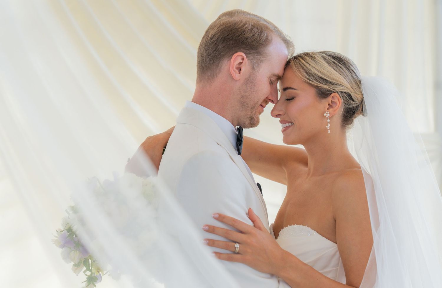 Romantic wedding couple portraits in white attire against light backdrop.