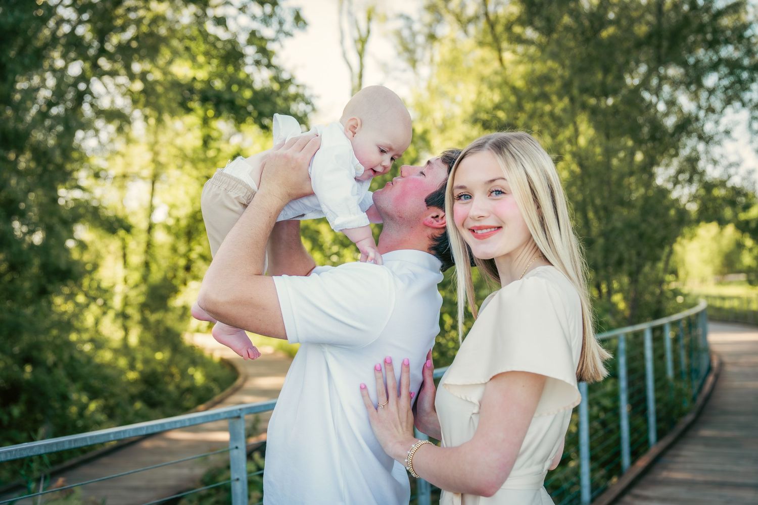 Happy couple poses together outdoors on a wooden bridge during golden hour sunset.