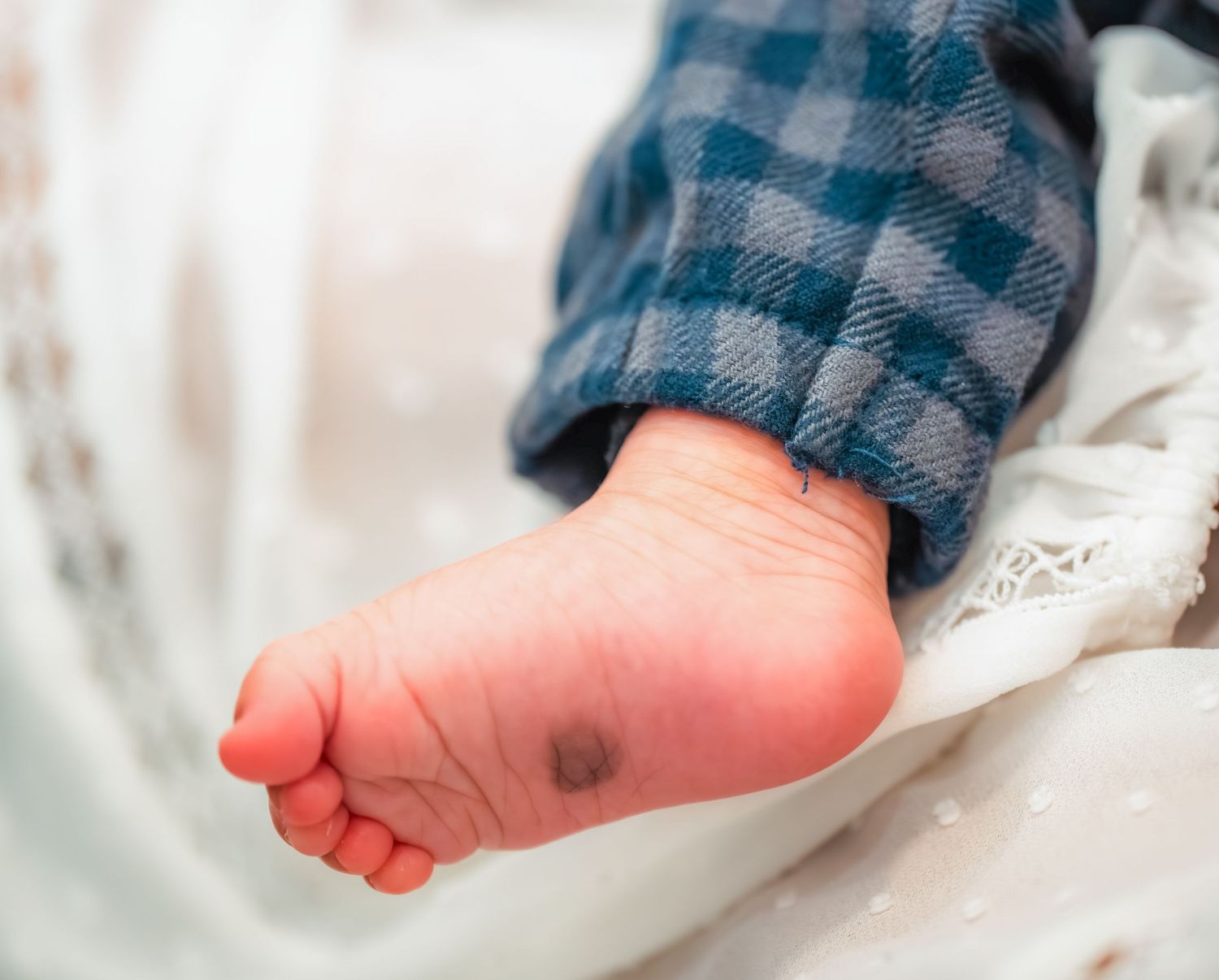 Close up of baby's tiny pink feet against white fabric.