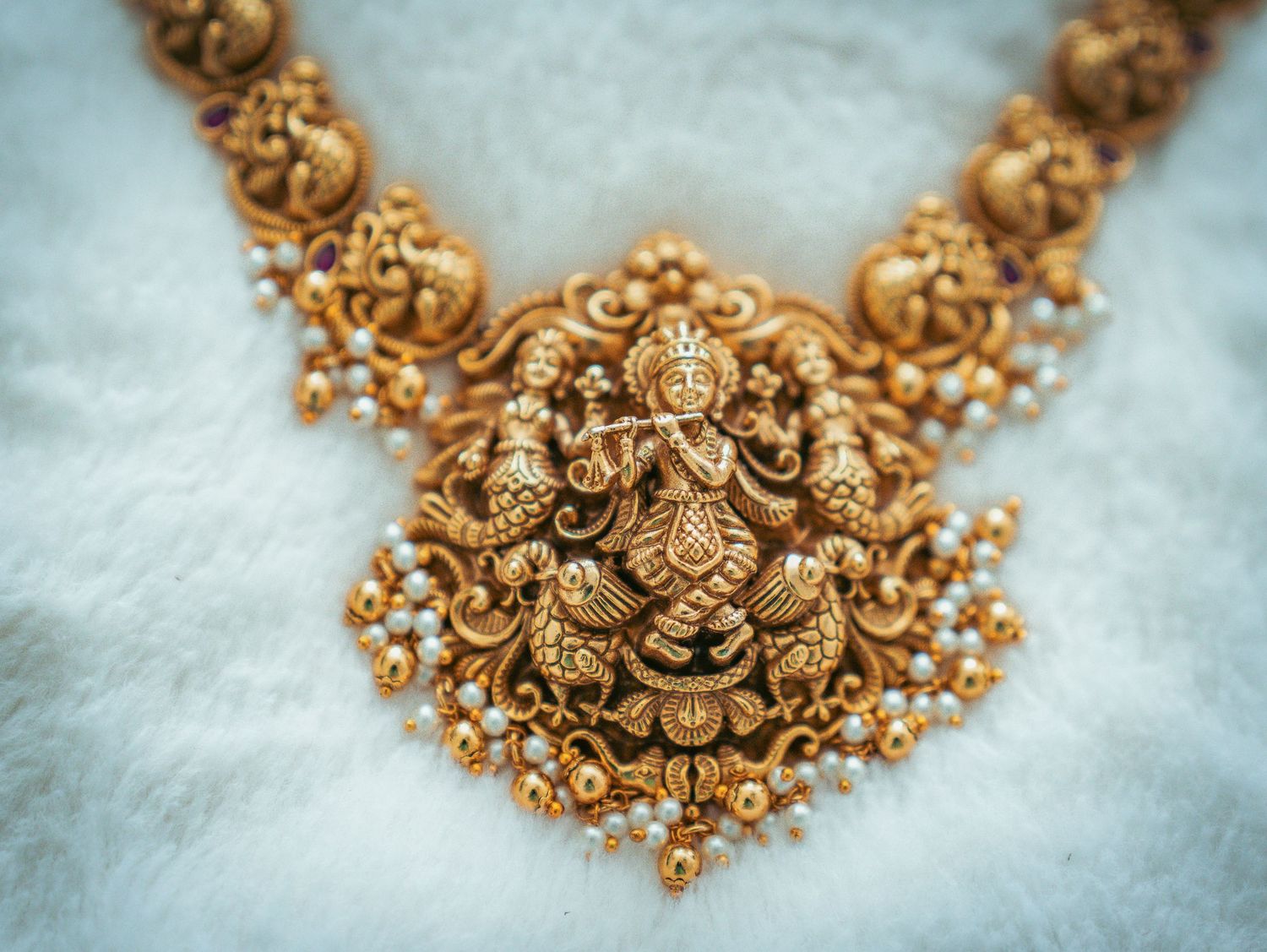An ornate gold temple jewelry necklace with intricate Goddess design and pearl details.