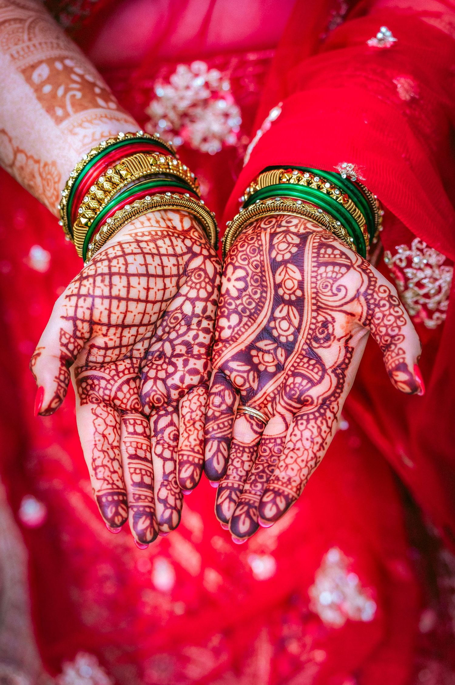 Intricate mehndi designs on hands displayed against red wedding attire.