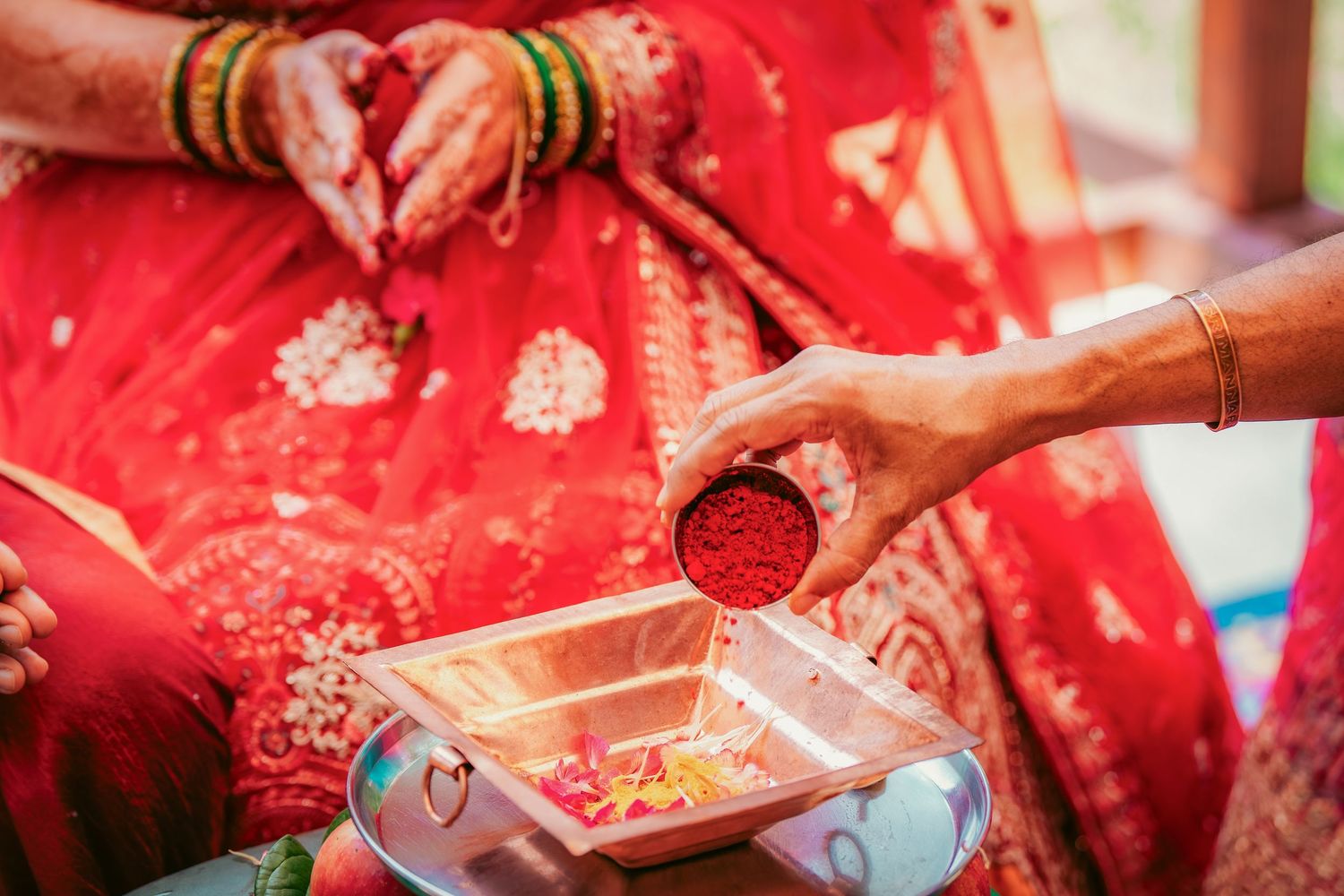 Detailed shots of hands during Indian wedding ritual with red and gold decorative elements.