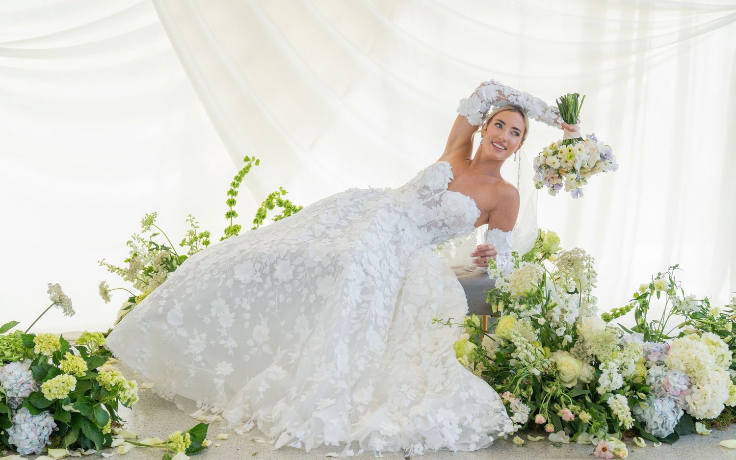 Elegant bridal portrait featuring a white lace gown and floral arrangements against a light backdrop.