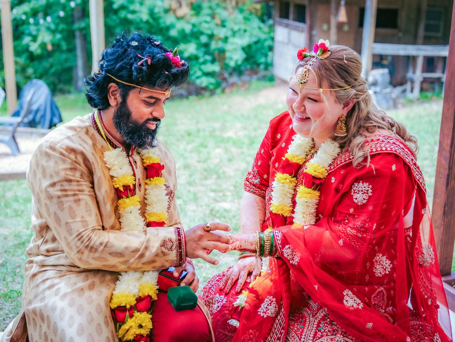 Couple exchanges playful moments during traditional Indian wedding rituals outdoors.