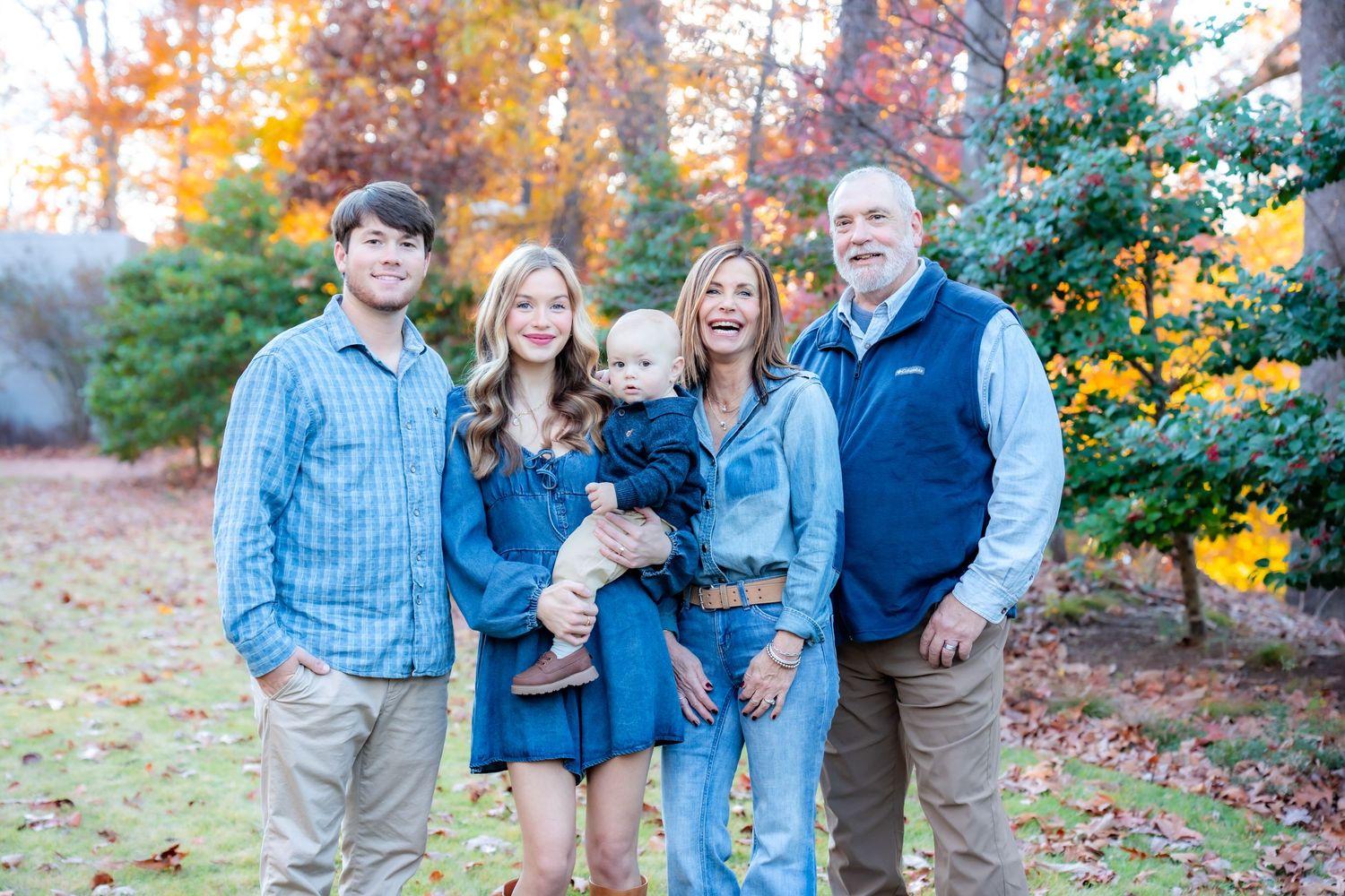 Multi-generational family photo session among colorful fall trees.