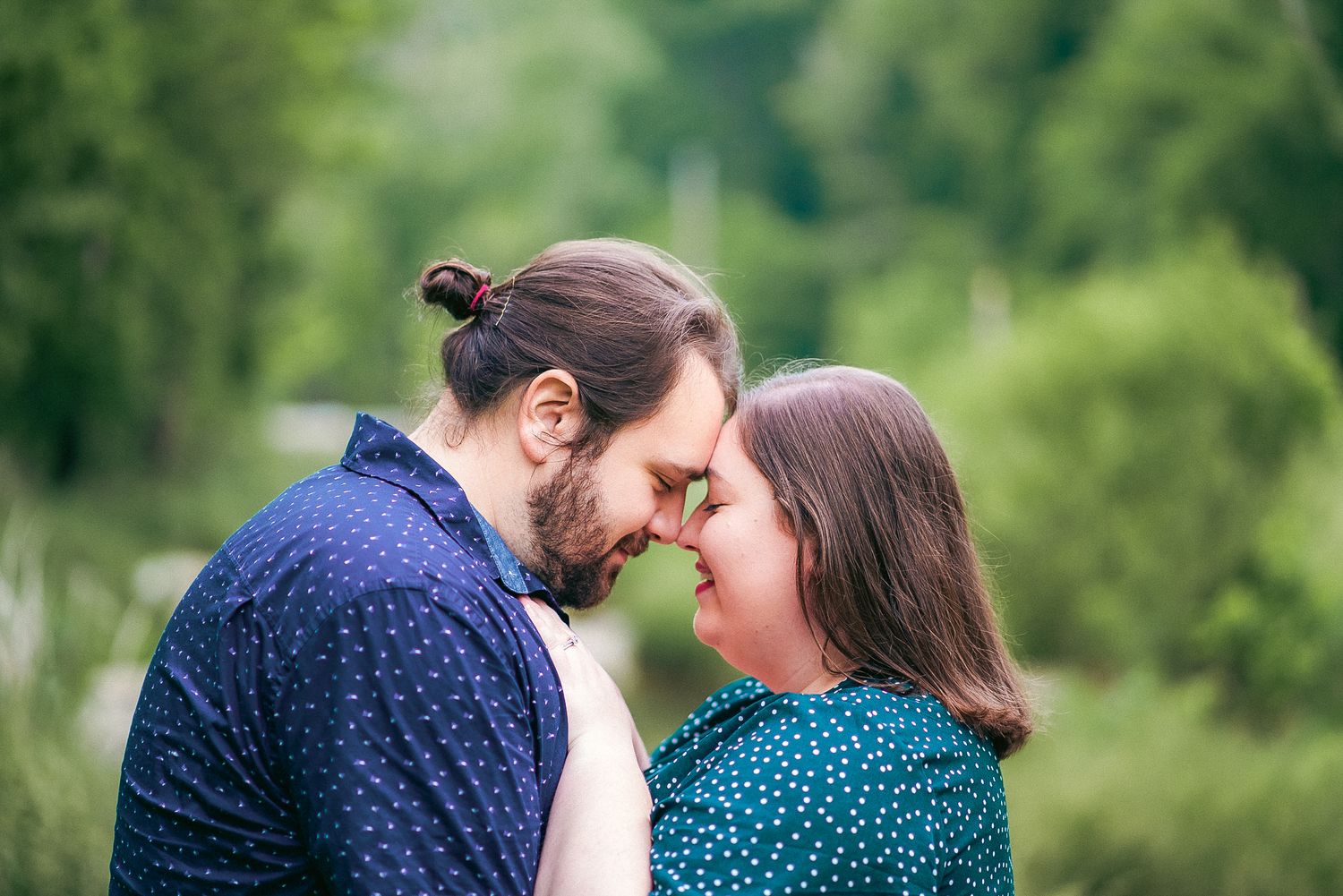 A romantic couple shares tender moments during an outdoor photo session in a park.