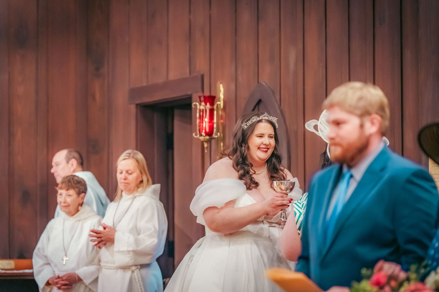 Wedding celebration in a traditional wooden church interior with warm lighting.