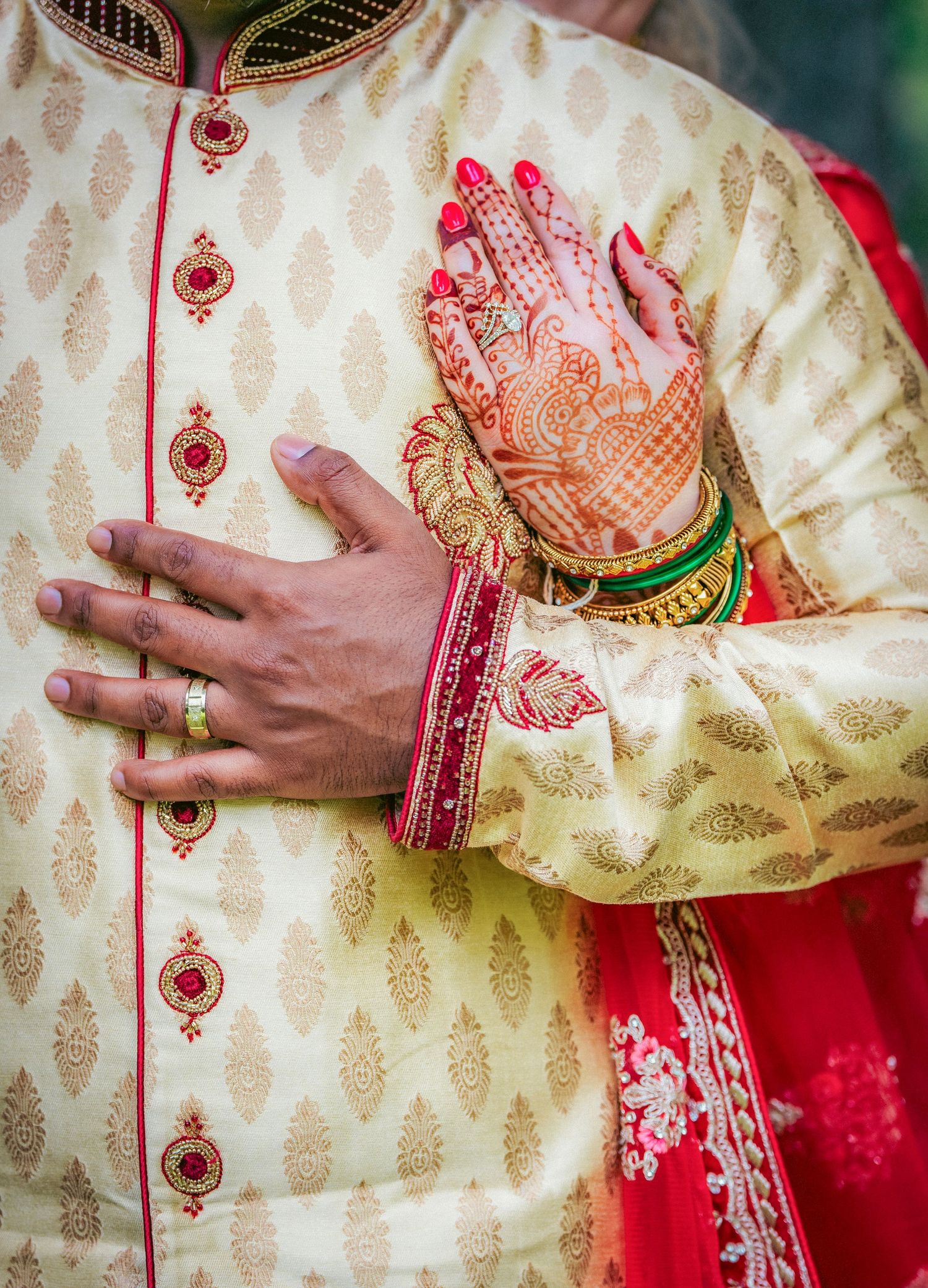 Traditional Indian groom's attire showing cream sherwani with detailed embroidery and red accents.