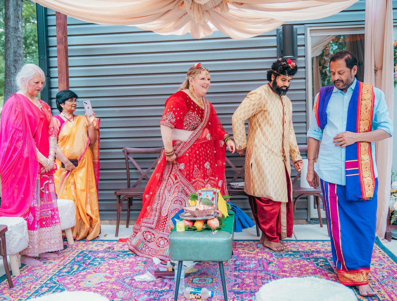 Wedding guests participate in traditional Indian ceremony games and rituals on a decorated stage.