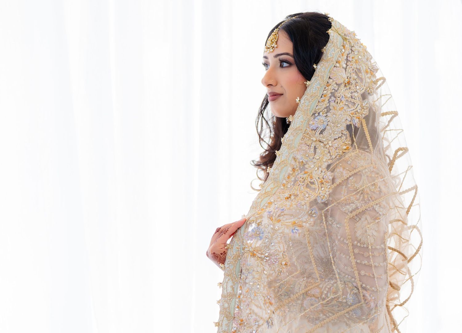 Traditional bridal portrait in cream colored embroidered outfit with delicate details.