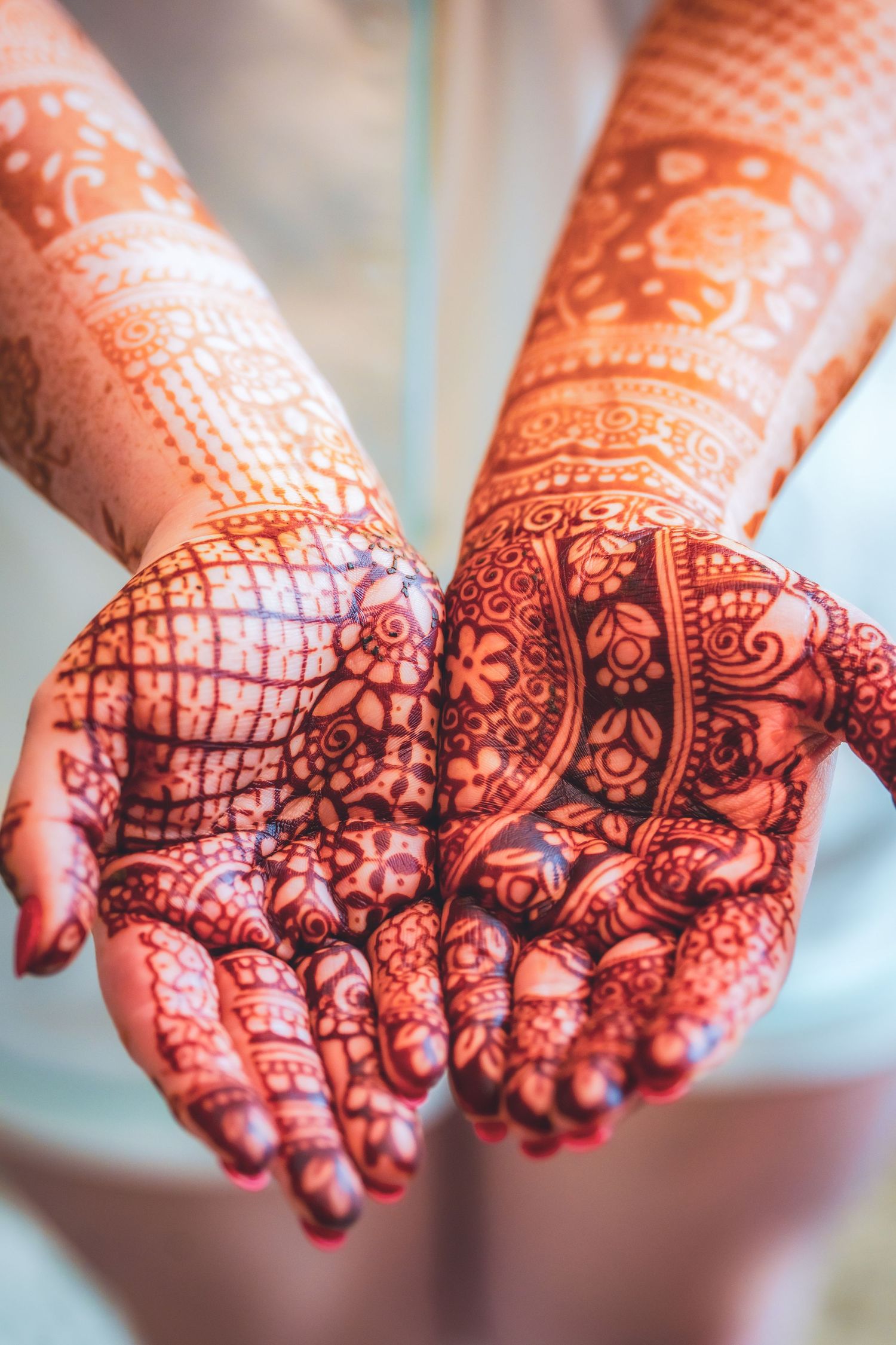 Intricate henna mehndi designs displayed on palms during Indian wedding preparations.