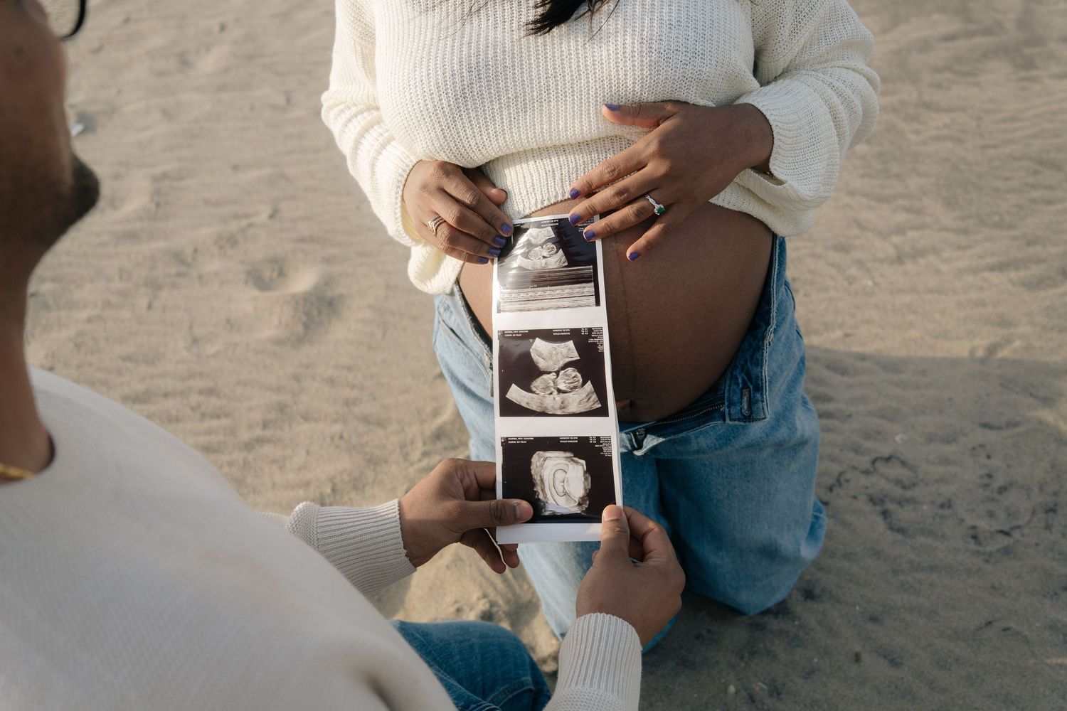 A series of black and white photos showing hands holding ultrasound images against a sandy background.