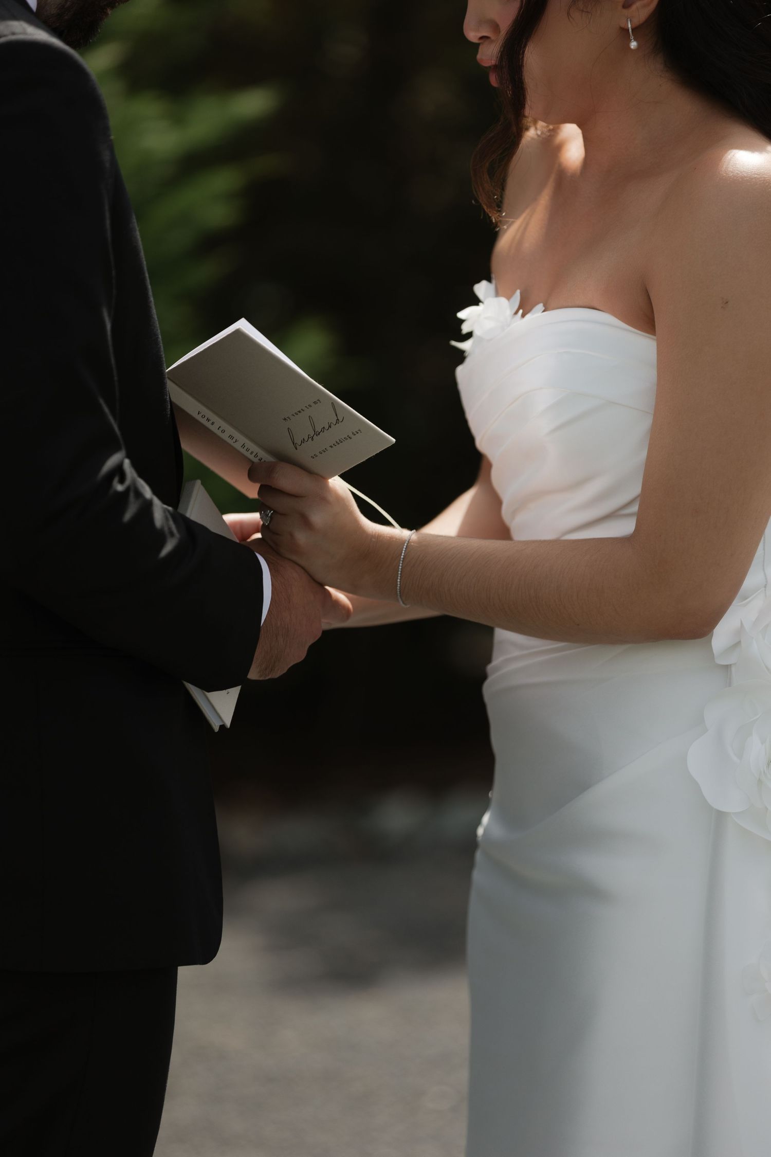 Bride and groom holding hands and exchanging vows during outdoor wedding ceremony.