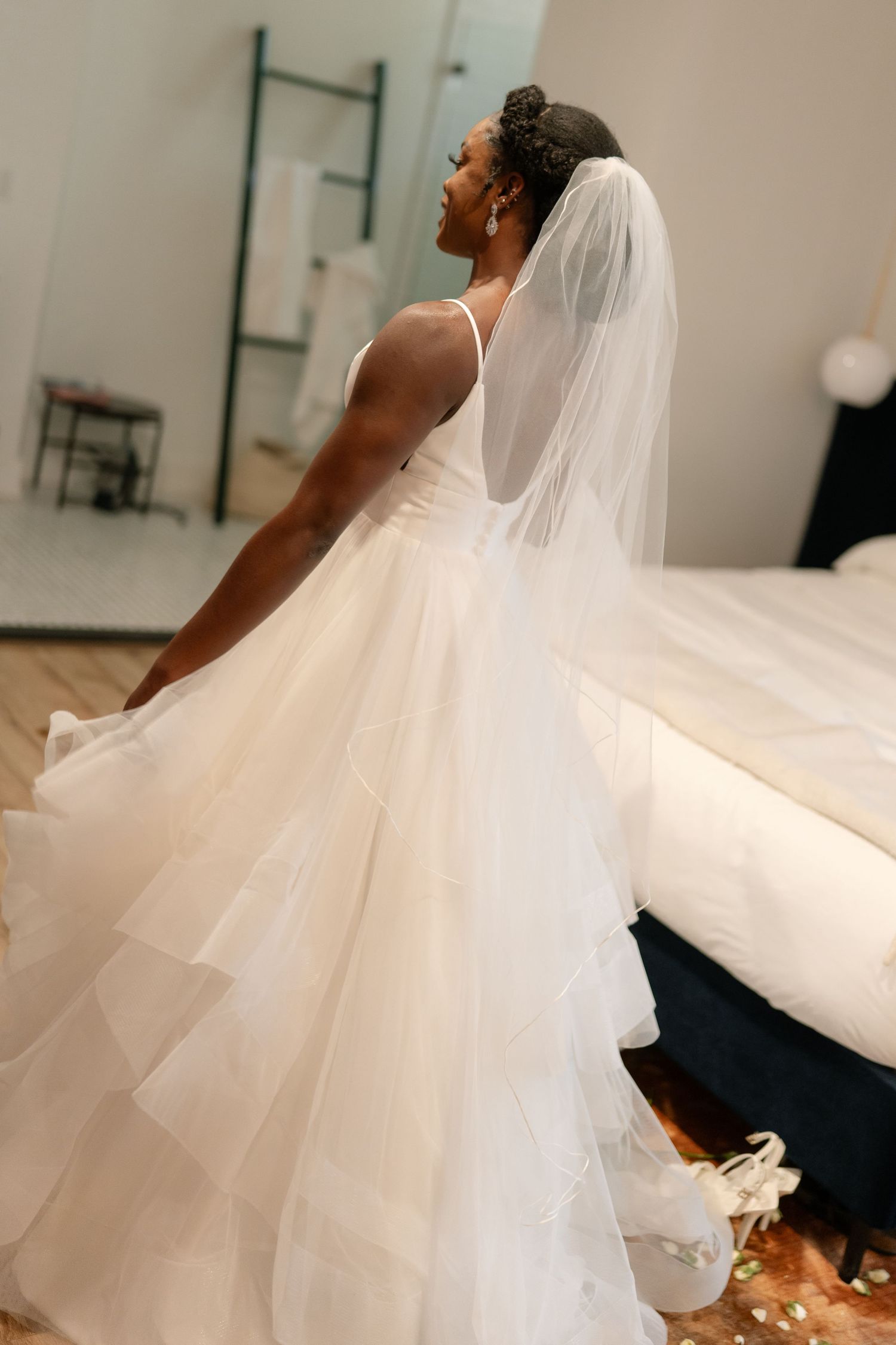 Side view of layered tulle wedding gown with flowing veil in natural light.