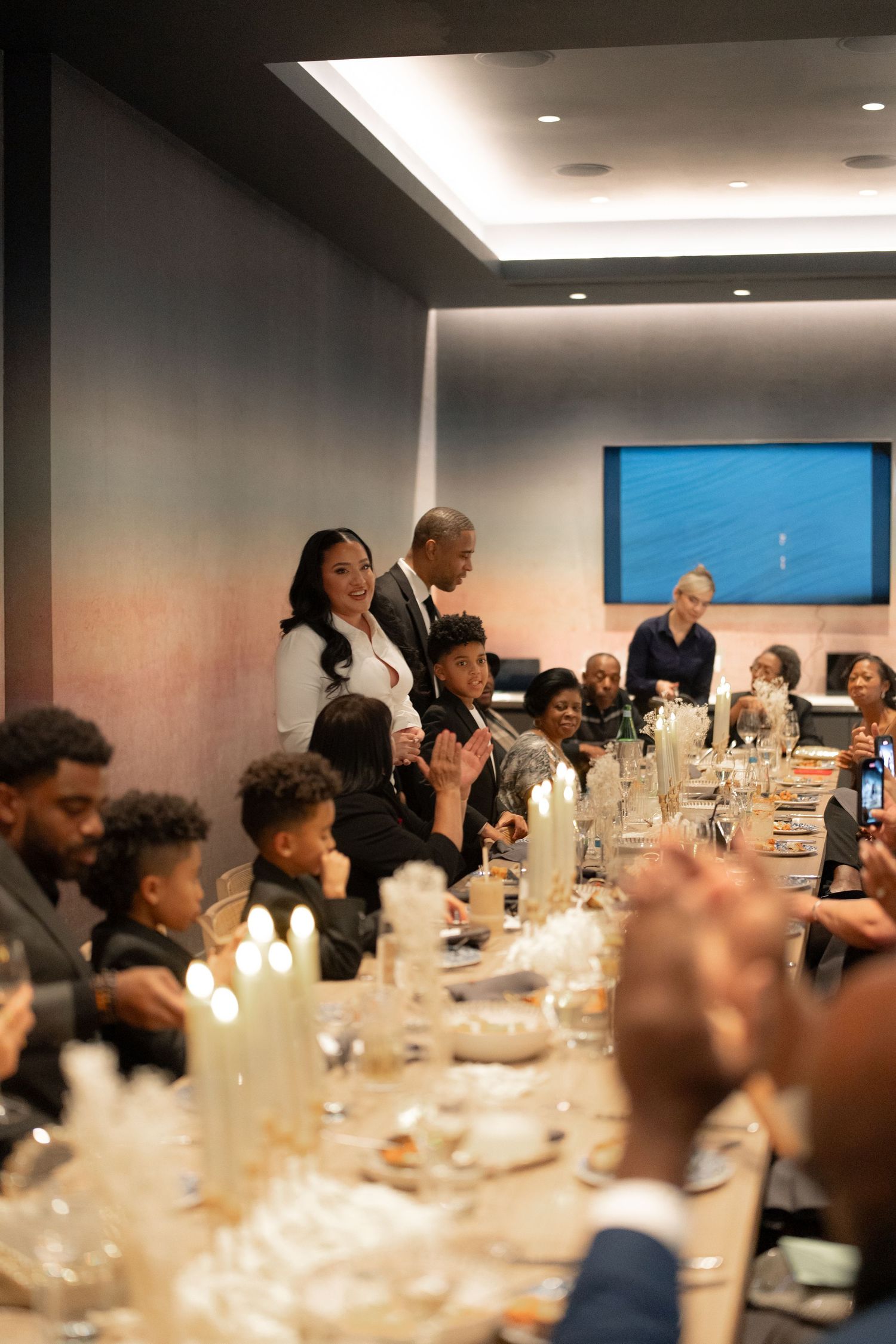 Wedding guests gathered around an elegantly set dinner table in a modern venue.