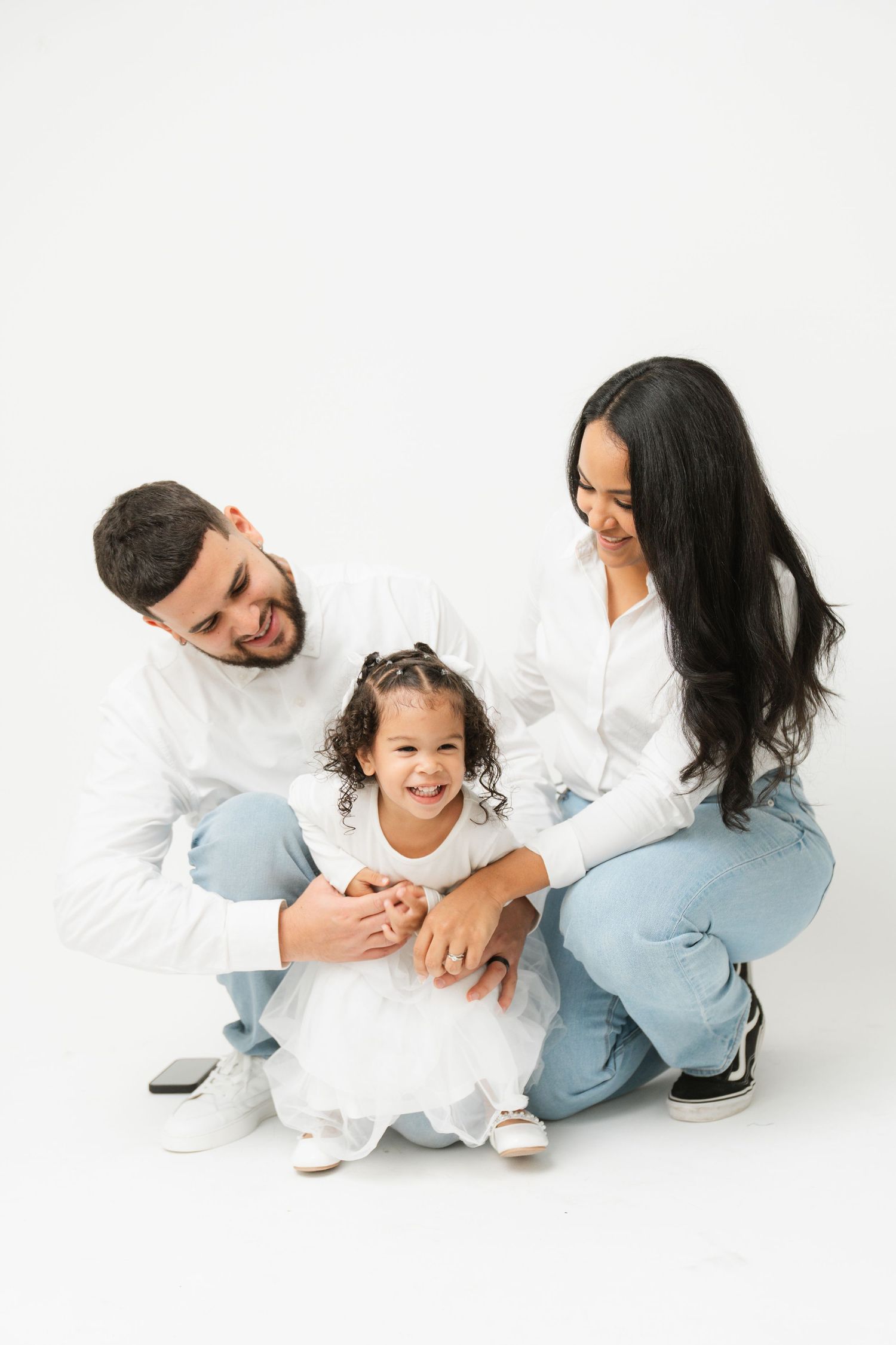 Family photo session with playful interactions on white background.