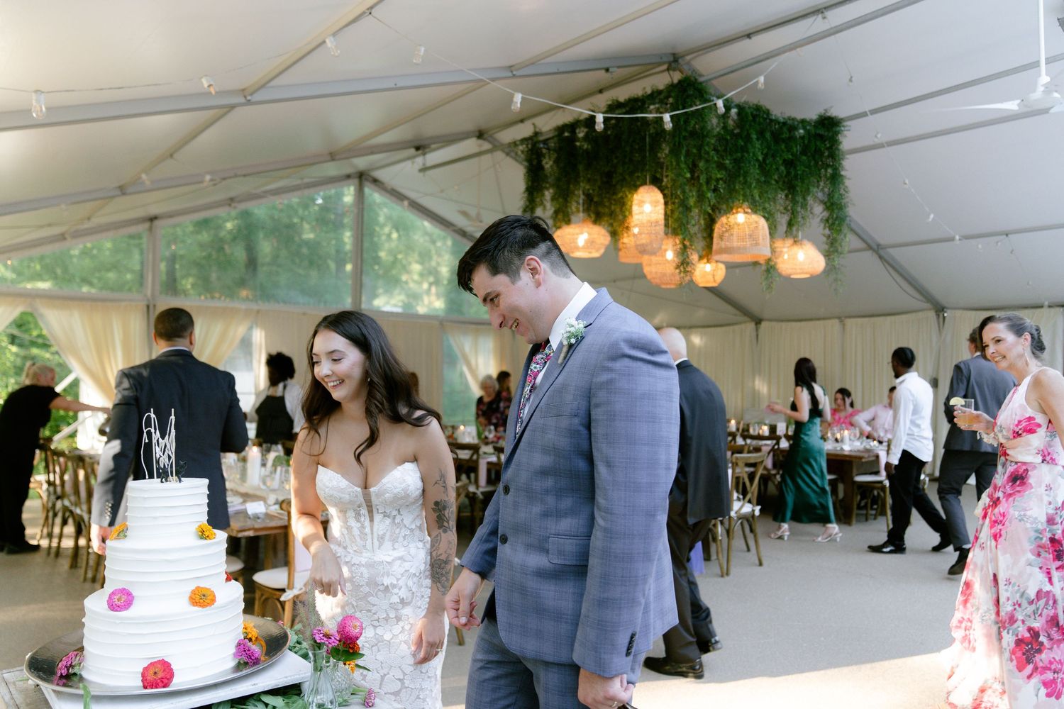 Wedding reception tent features elegant table settings and hanging lights for evening celebration.
