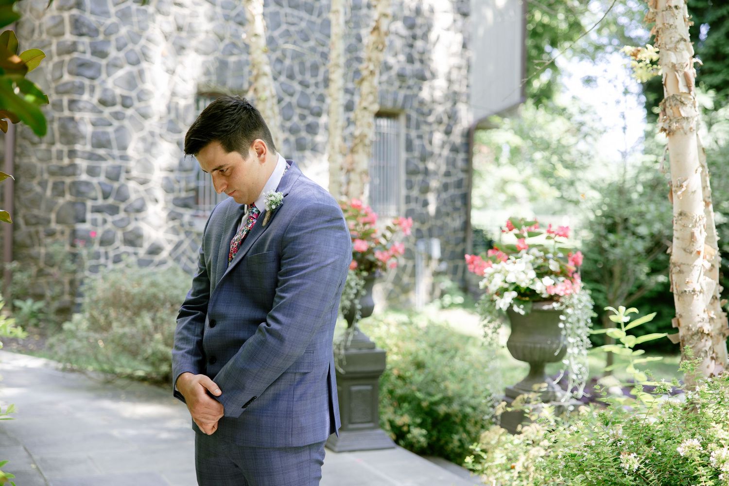 Wedding couple shares intimate moment in lush garden setting with stone walls.