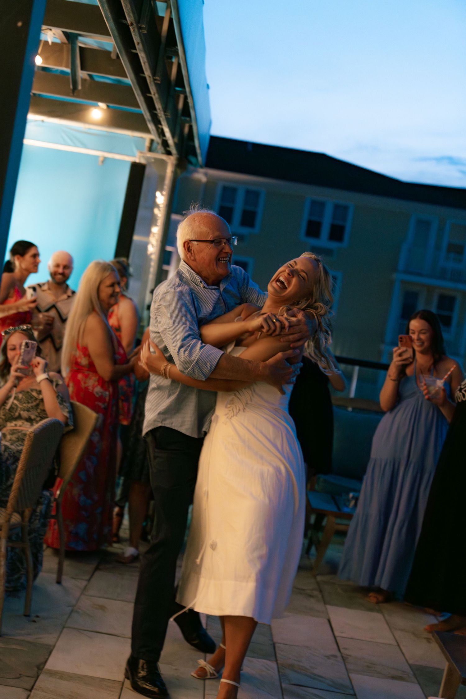 Wedding guests dance together on a patio during an evening celebration.