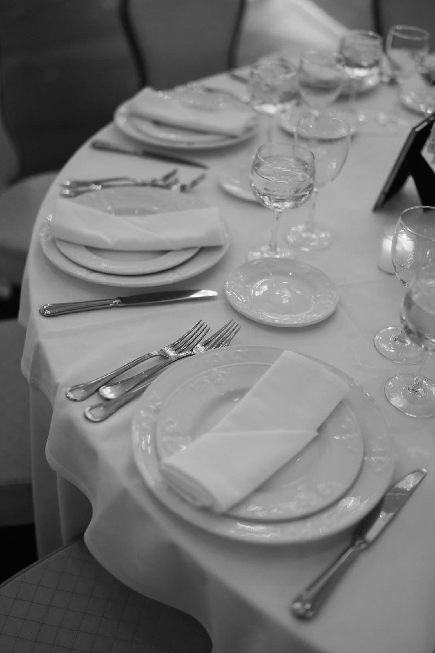 Elegant table setting with white linens, fine china, and crystal wine glasses.