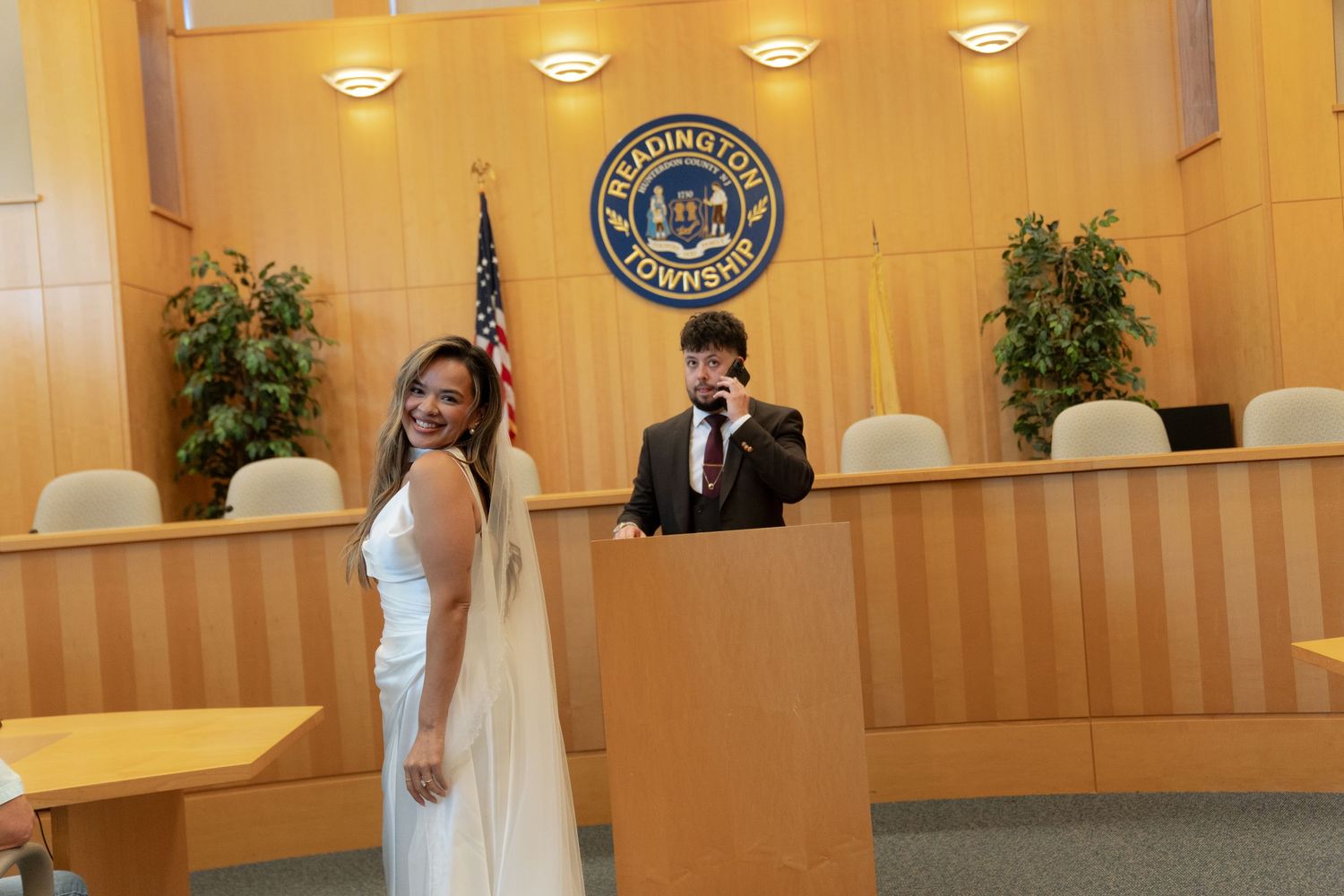 Couple celebrating civil wedding ceremony at Reading Township municipal building with American flag and official seal.