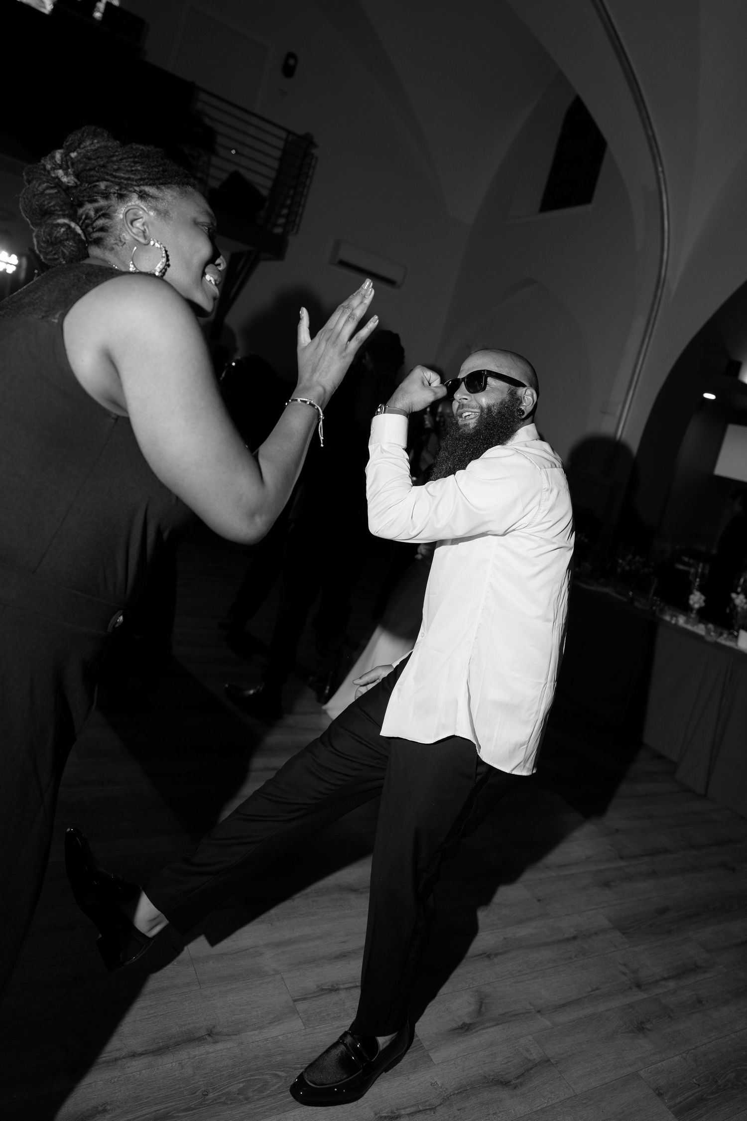 Black and white photo of guests dancing at wedding reception.