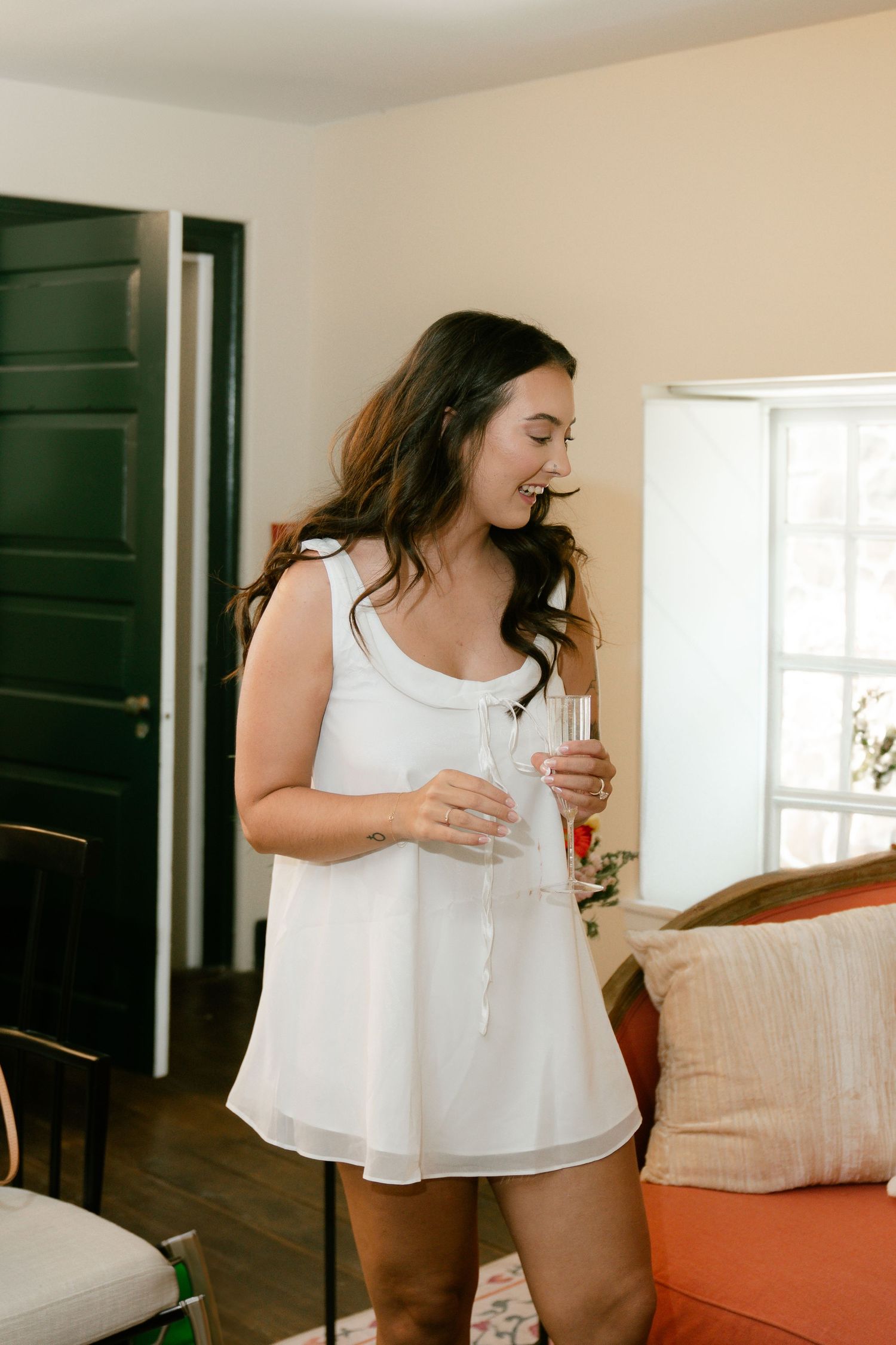 Woman in white sleeveless top lounging at home in a bright interior setting.