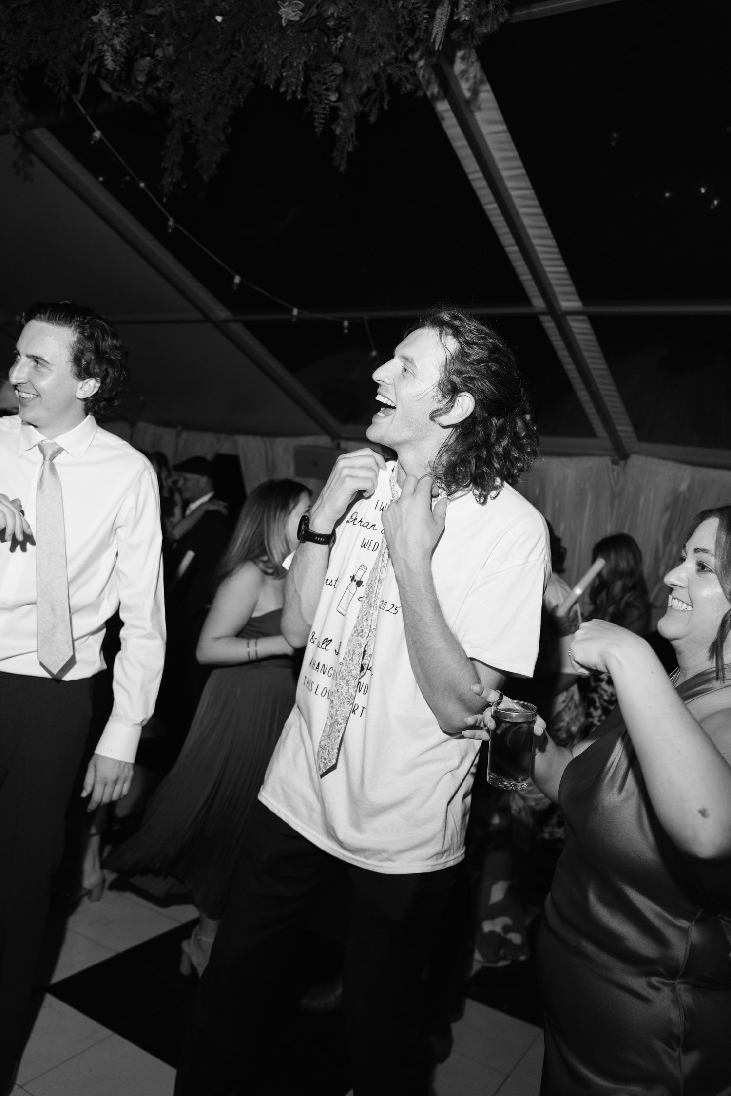 Black and white photo of energetic dancing at a nighttime wedding reception.