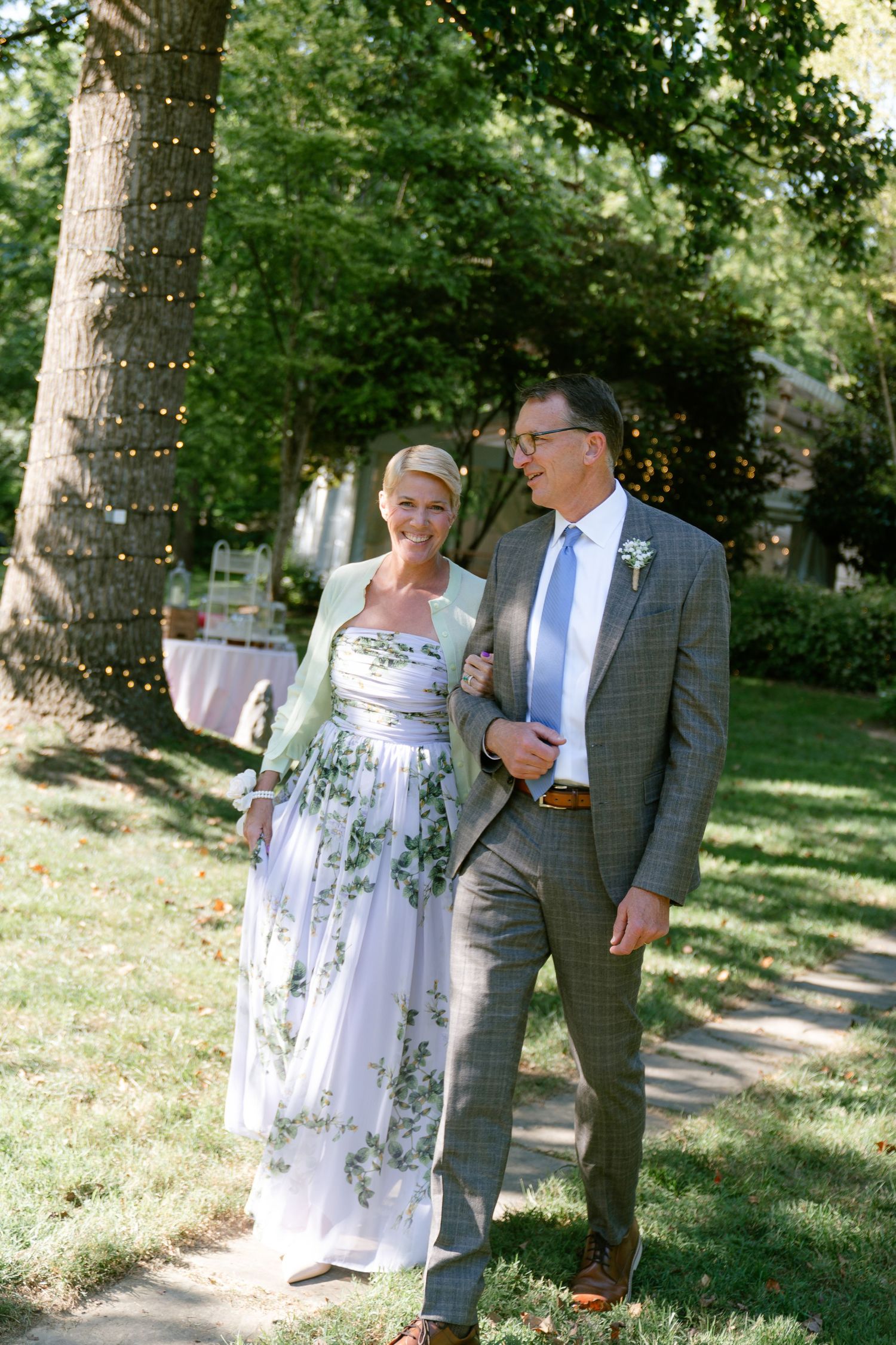 A couple takes a romantic stroll together on a sunny day in a lush garden setting.