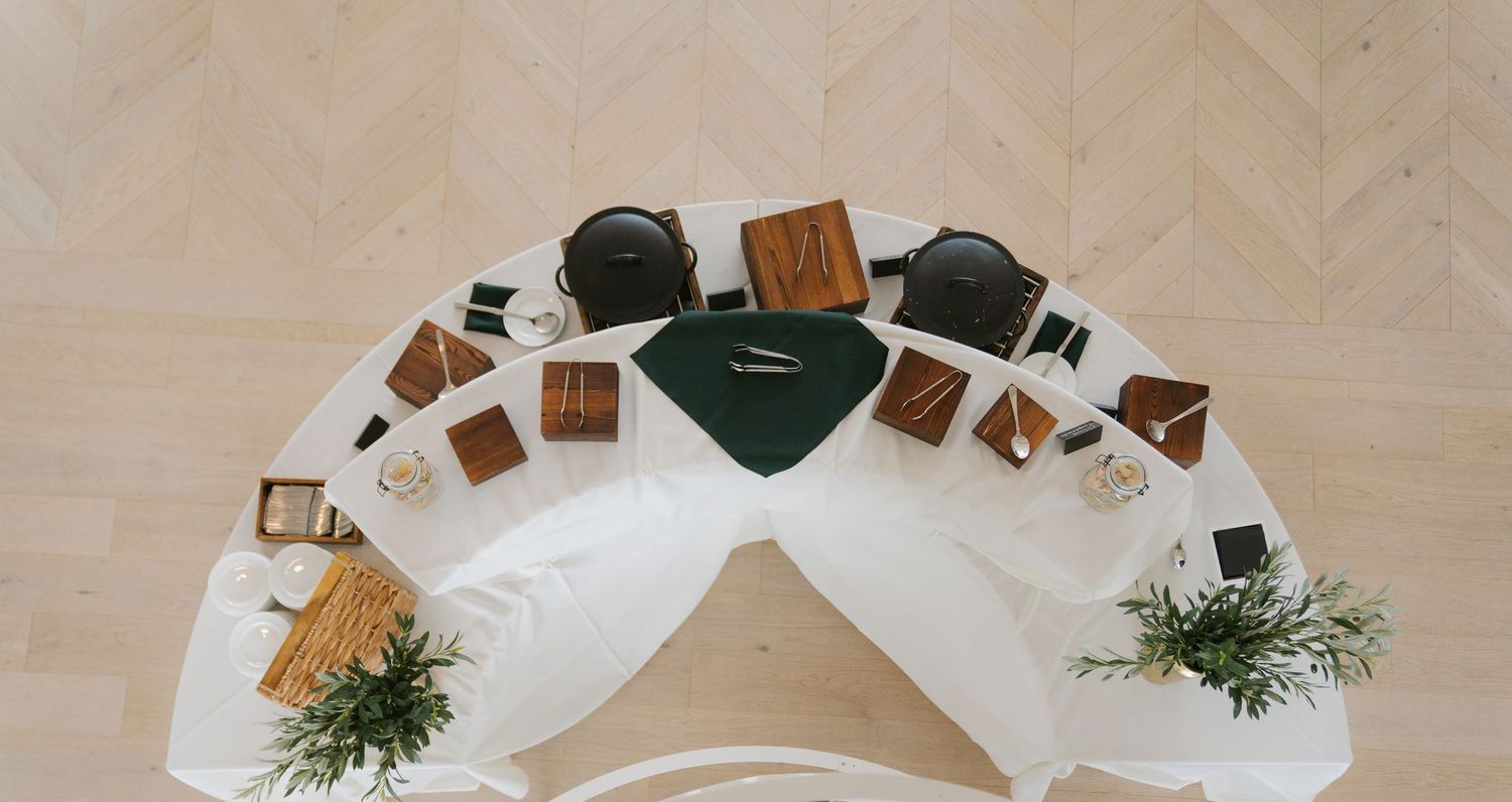 Chocolate squares arranged in a pattern on a wooden surface with fresh herbs and white plates.