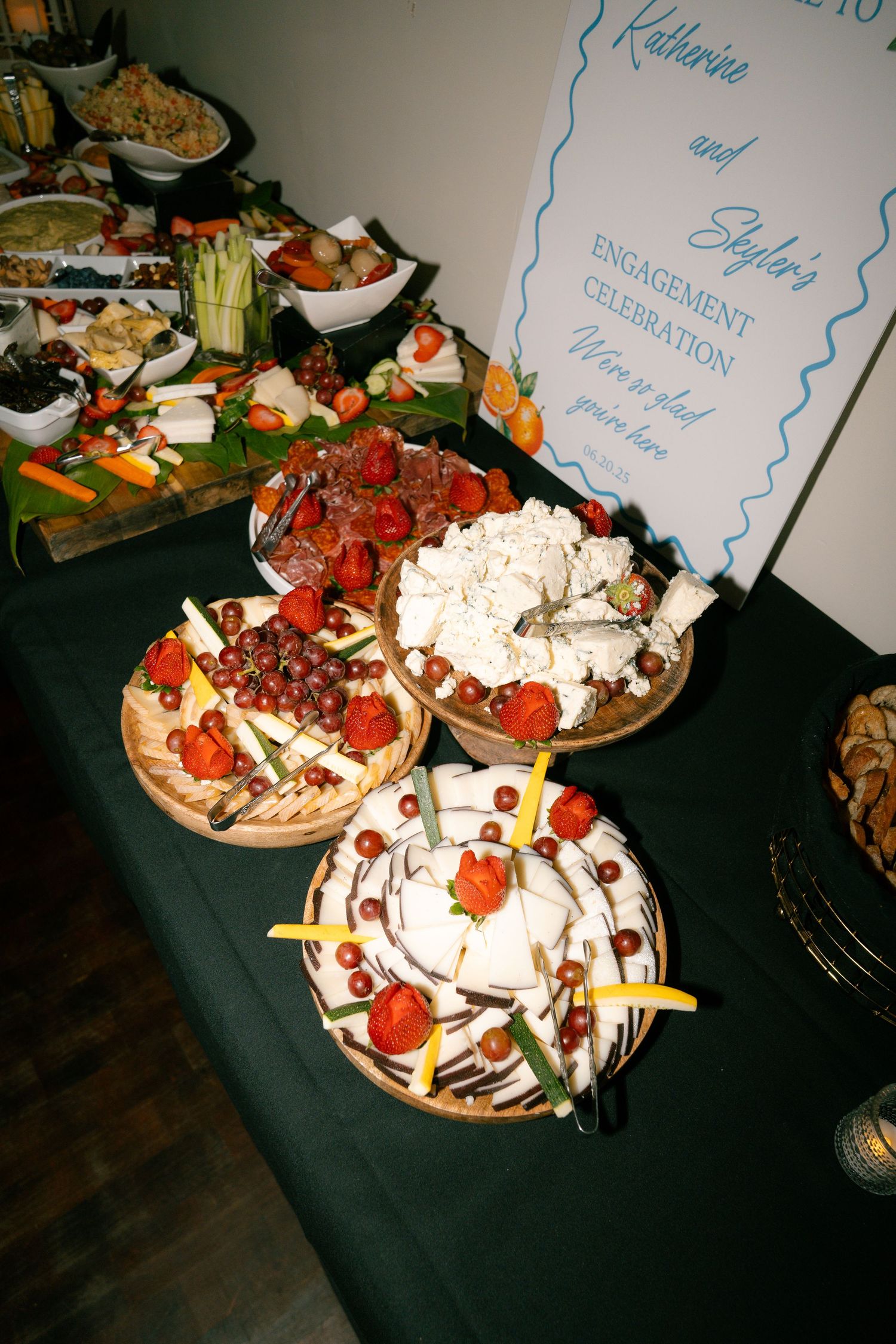 Appetizer platter with cheese, meats, and vegetables arranged on a black tablecloth.
