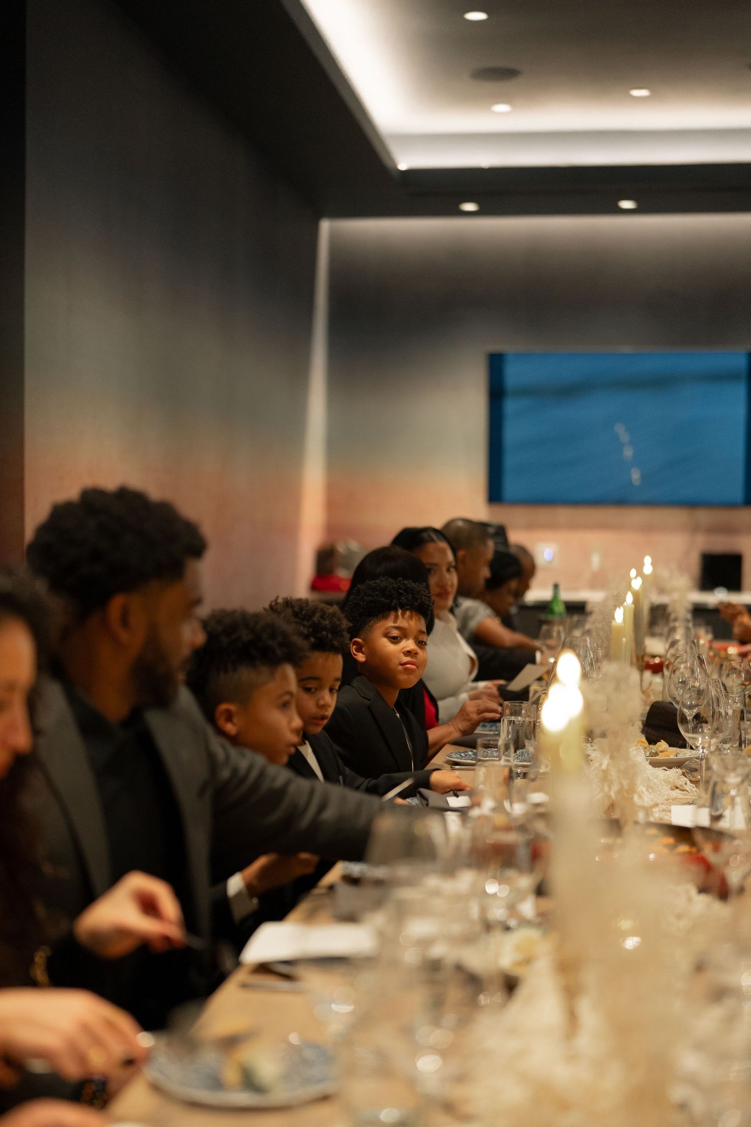 An elegant dinner setting with glassware and candles on a long table in a modern dining room.