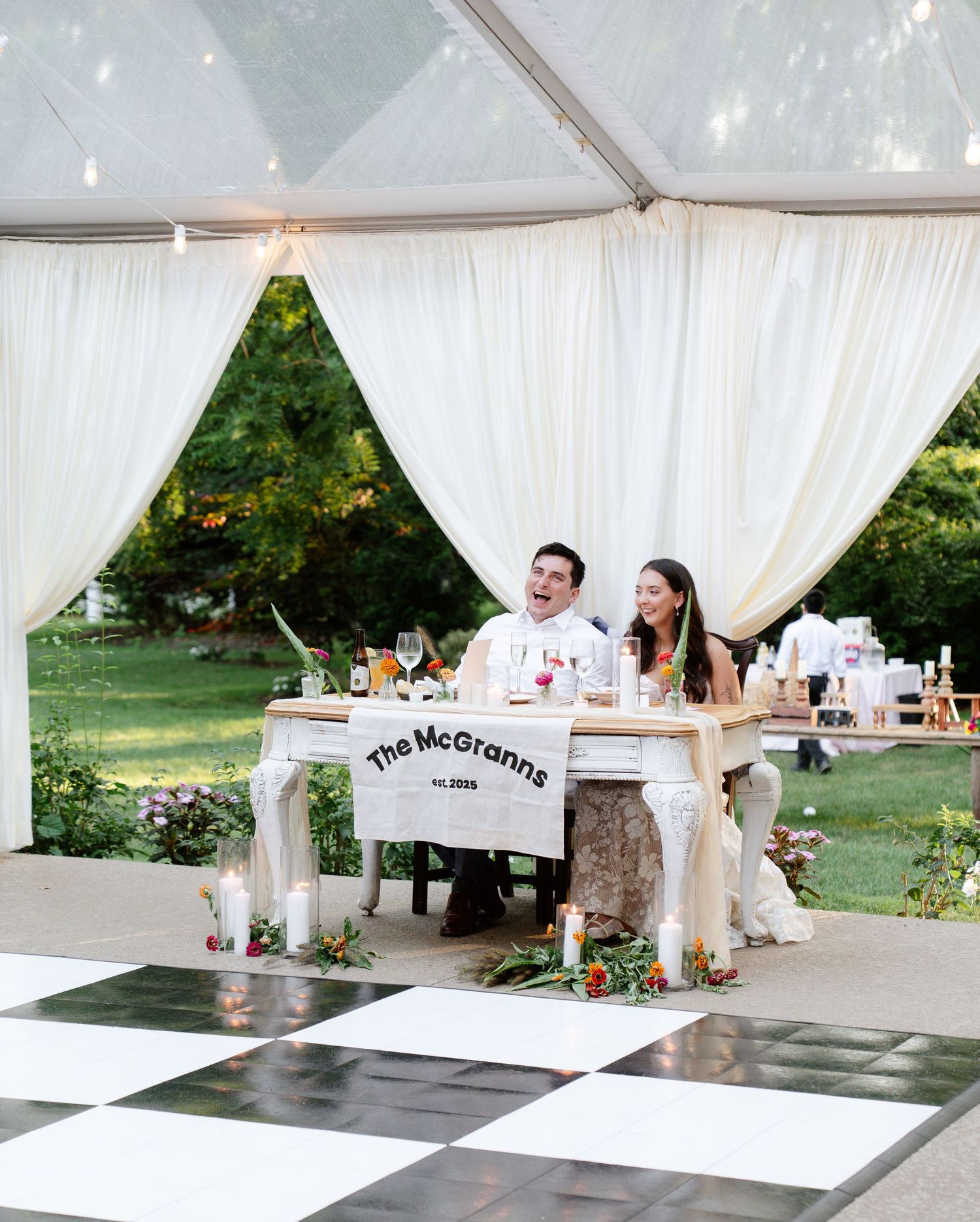 White draped tent interior with custom signage and wedding reception tables.
