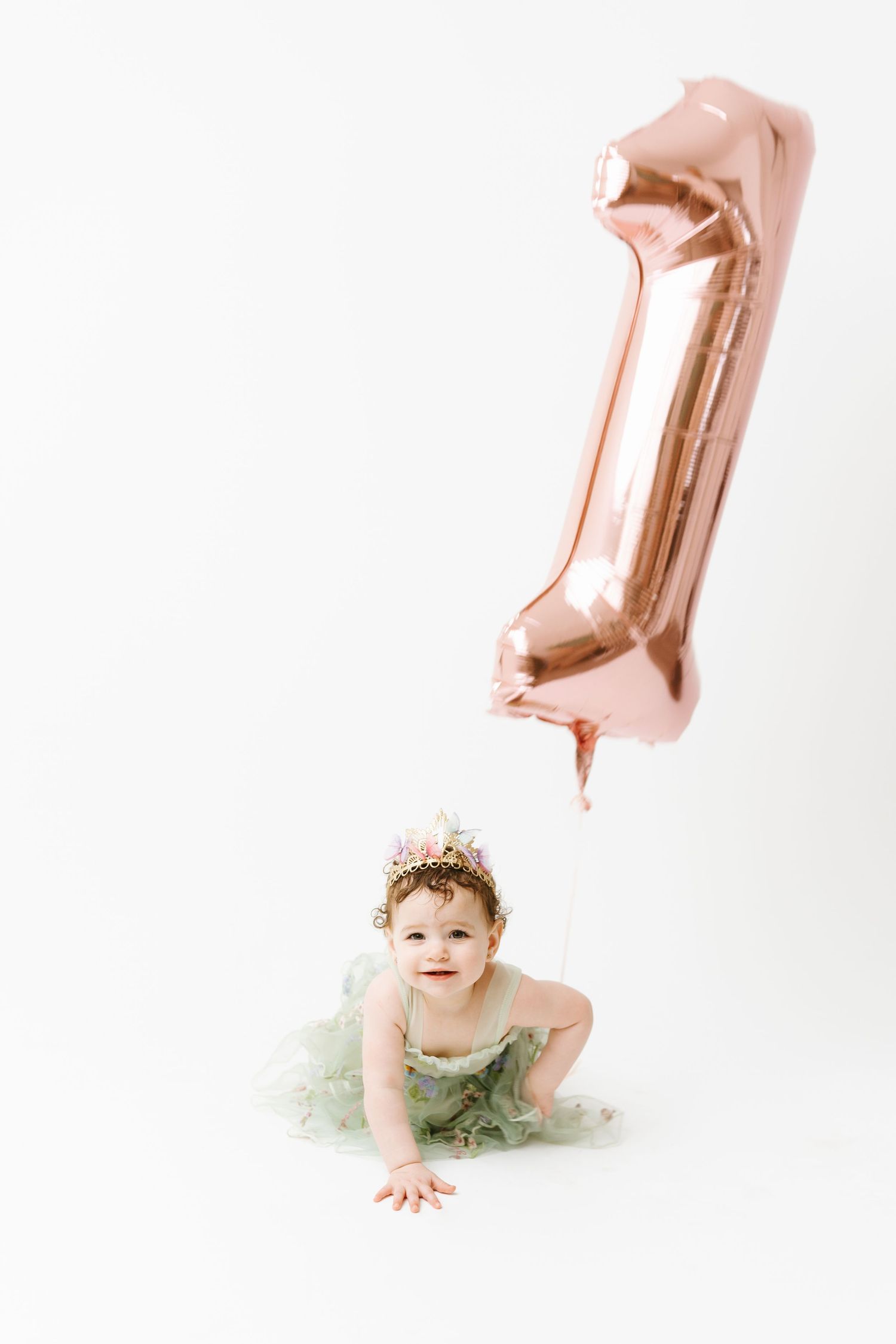 Baby milestone photo with rose gold number one balloon decoration.