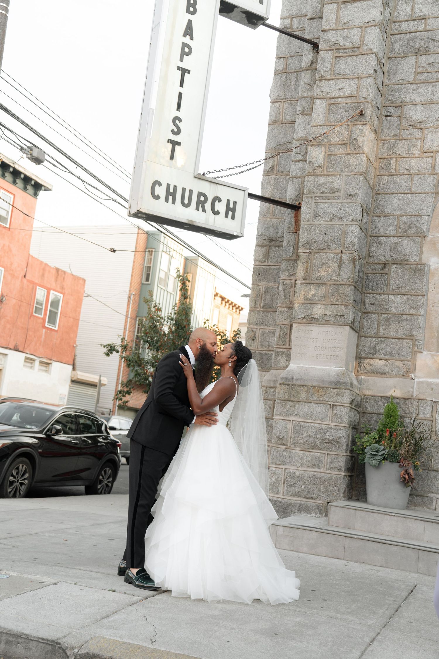 Wedding couple shares a romantic moment outside a stone church building.
