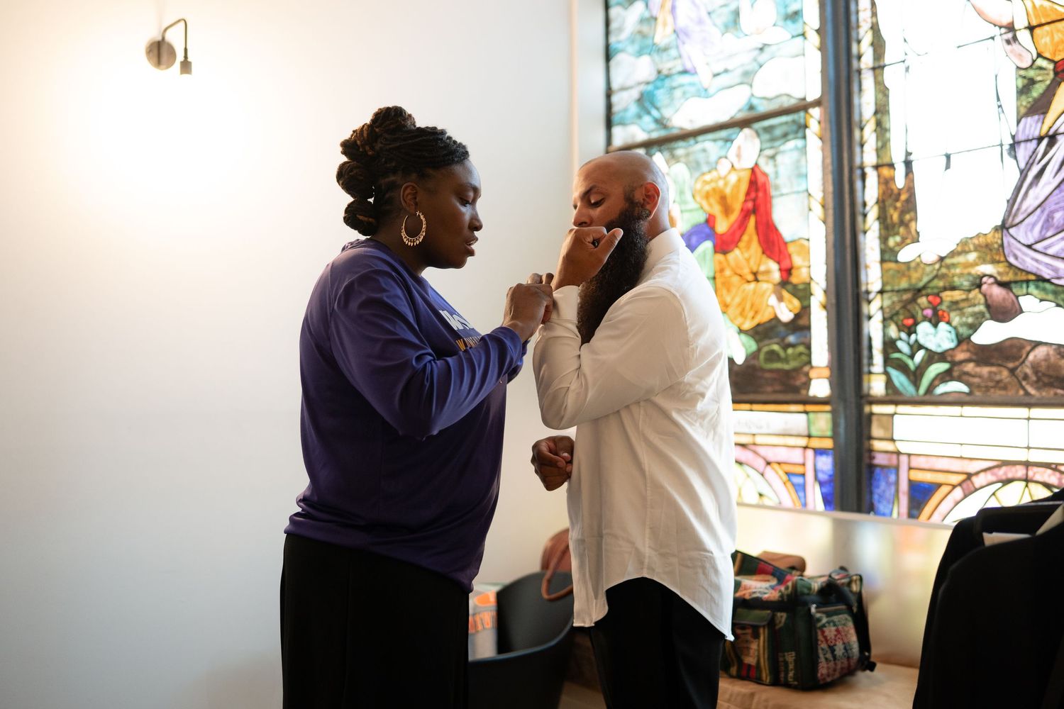 Two people interacting in an office space with stained glass windows in the background.