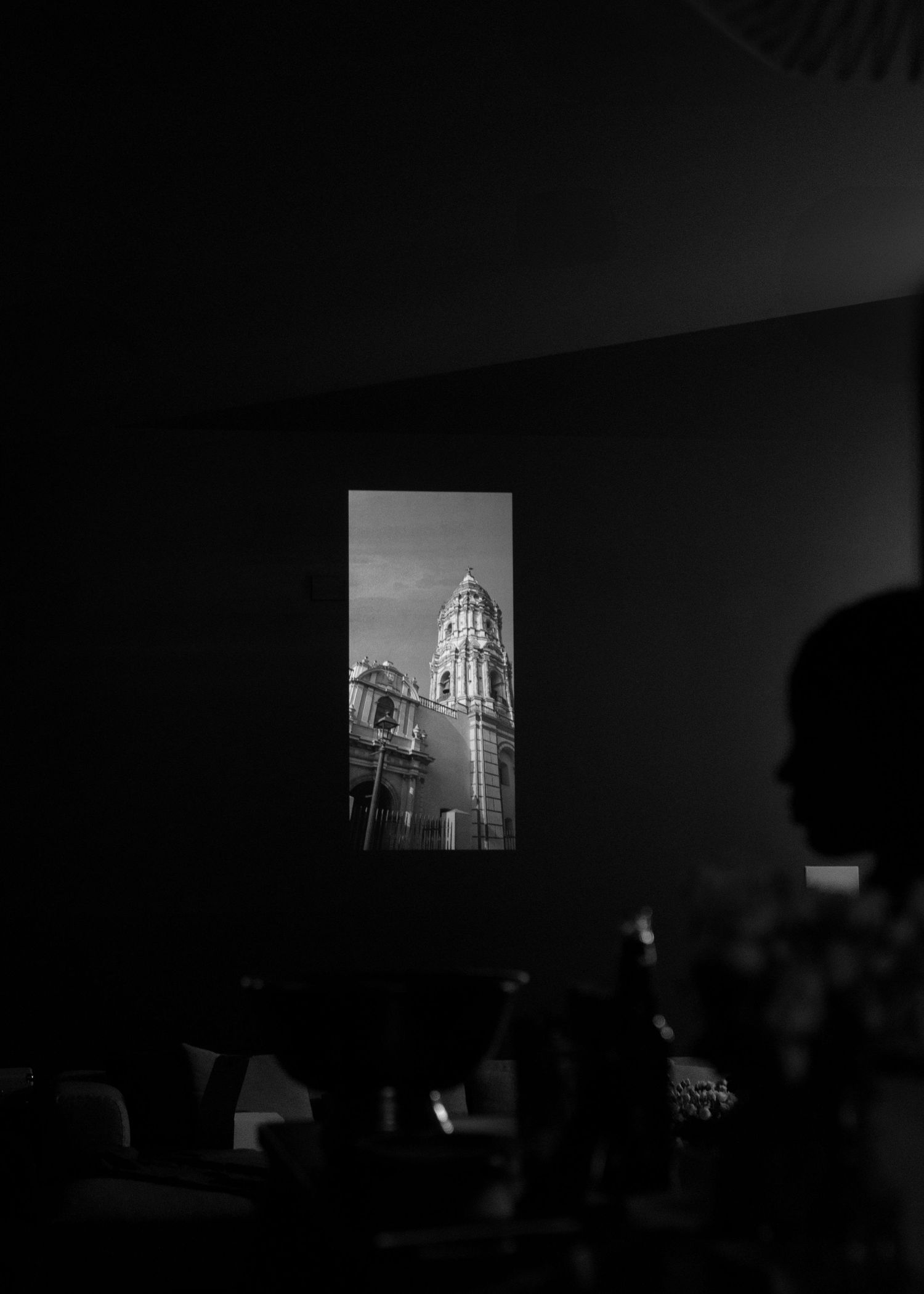 Dark room with projected architectural images on screen during presentation.