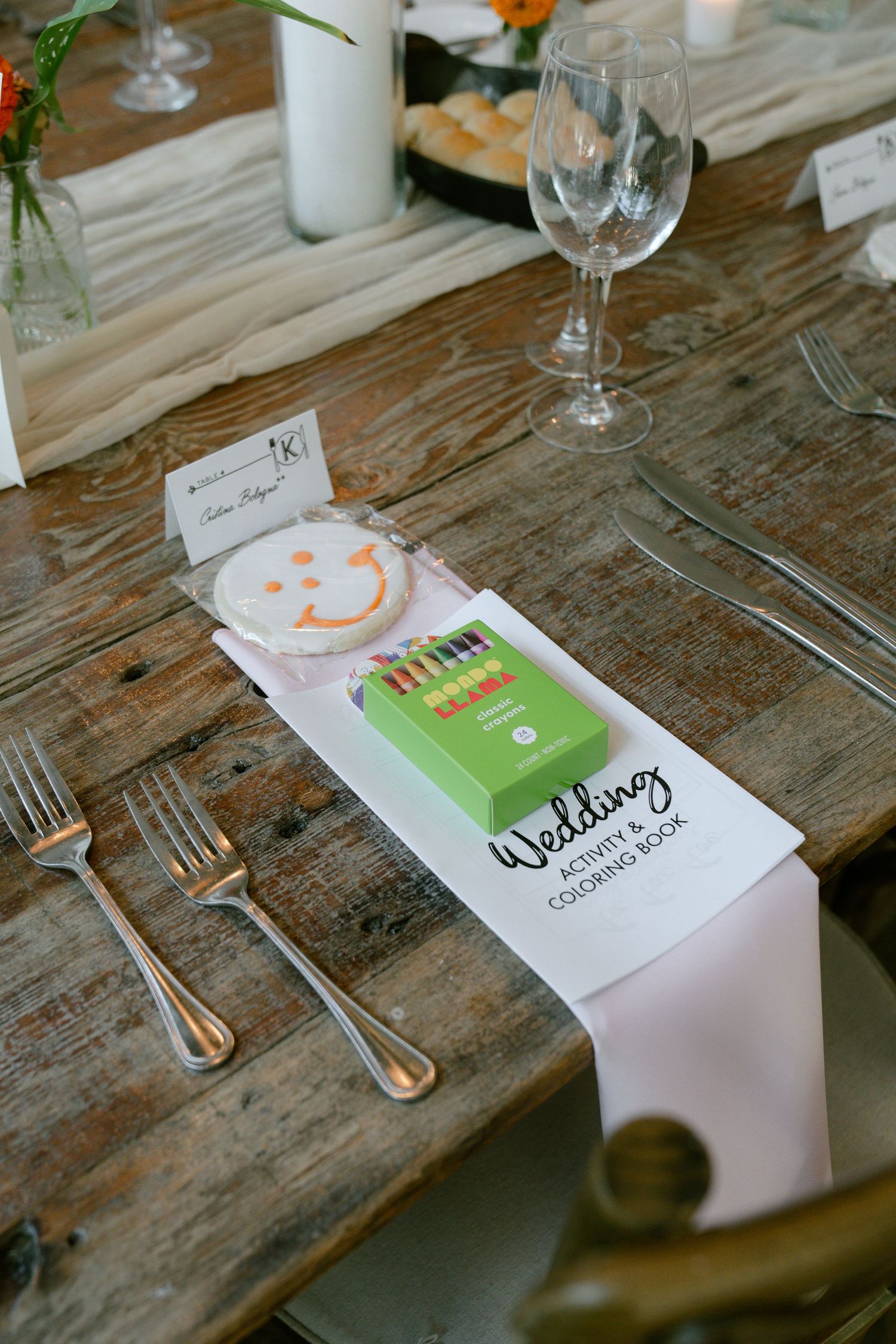 Wedding reception place settings on rustic wooden tables with handwritten name cards.