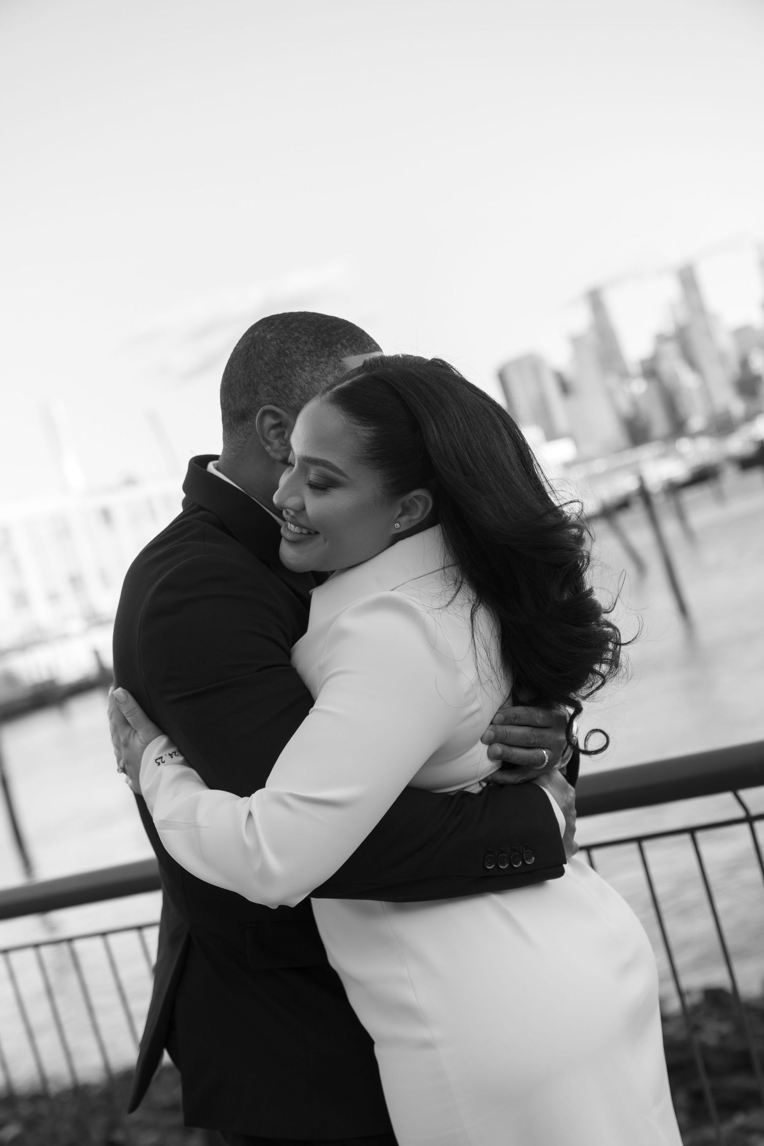 Black and white photos of newlyweds embracing by waterfront.
