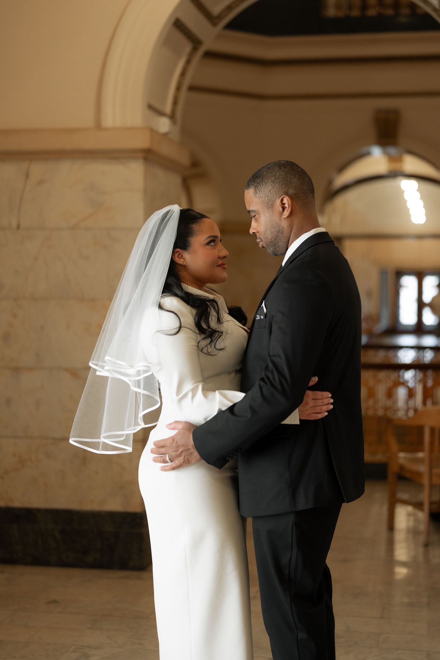 A romantic wedding photo series showing a couple in an elegant indoor venue with stone architecture.