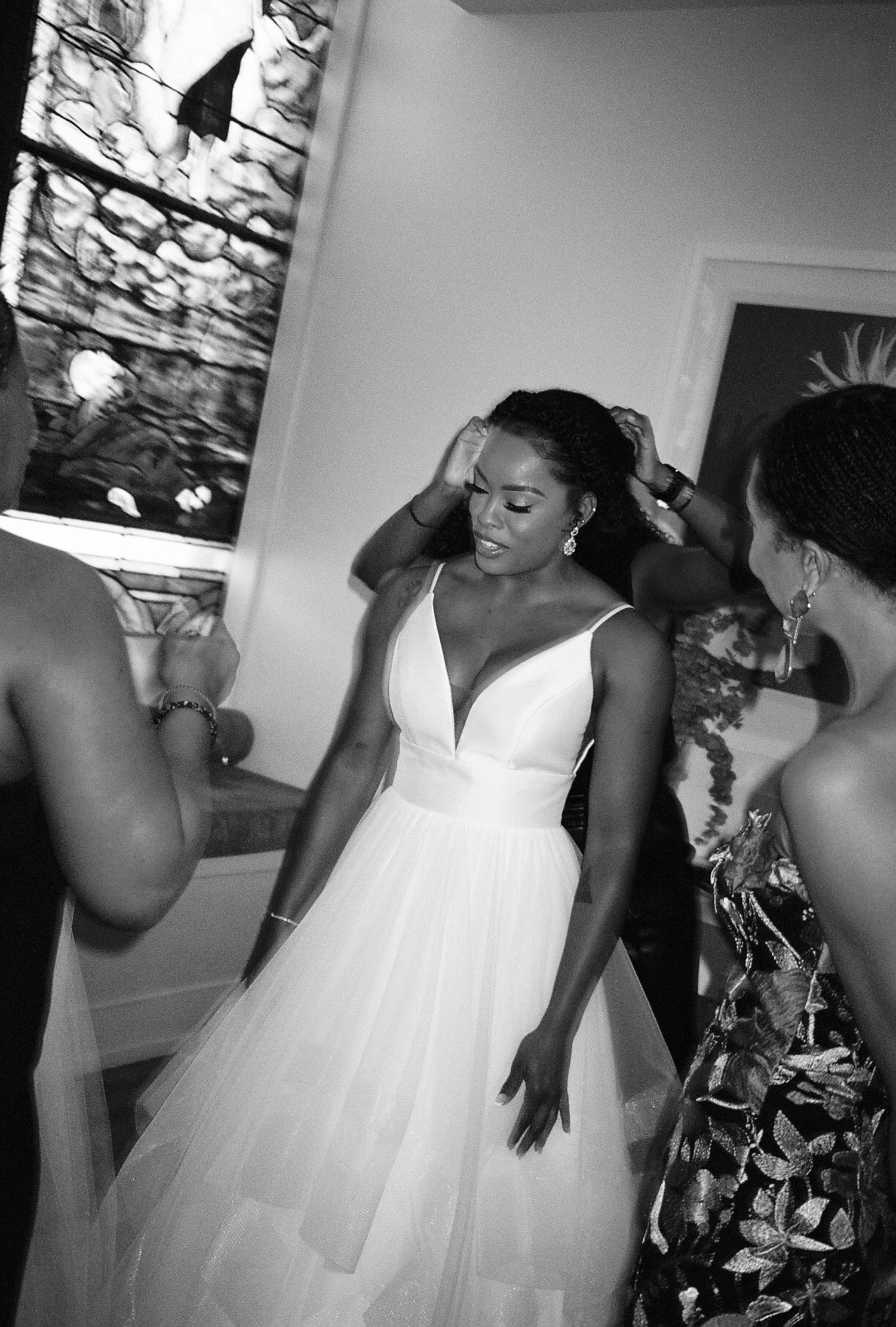 A bride in a flowing white V-neck gown getting ready with her bridal party.