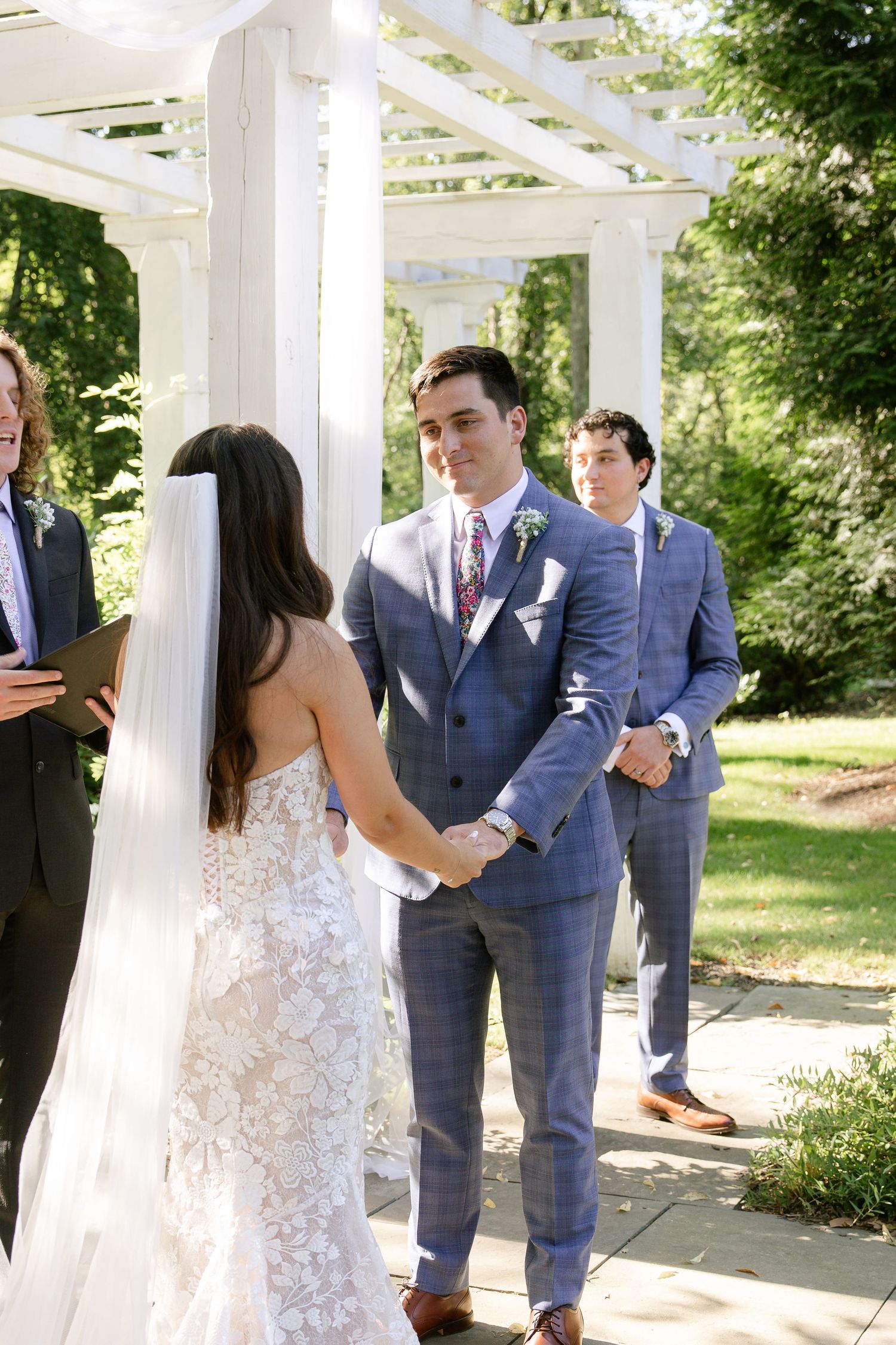 Wedding ceremony moments captured under a white pergola in a garden setting.